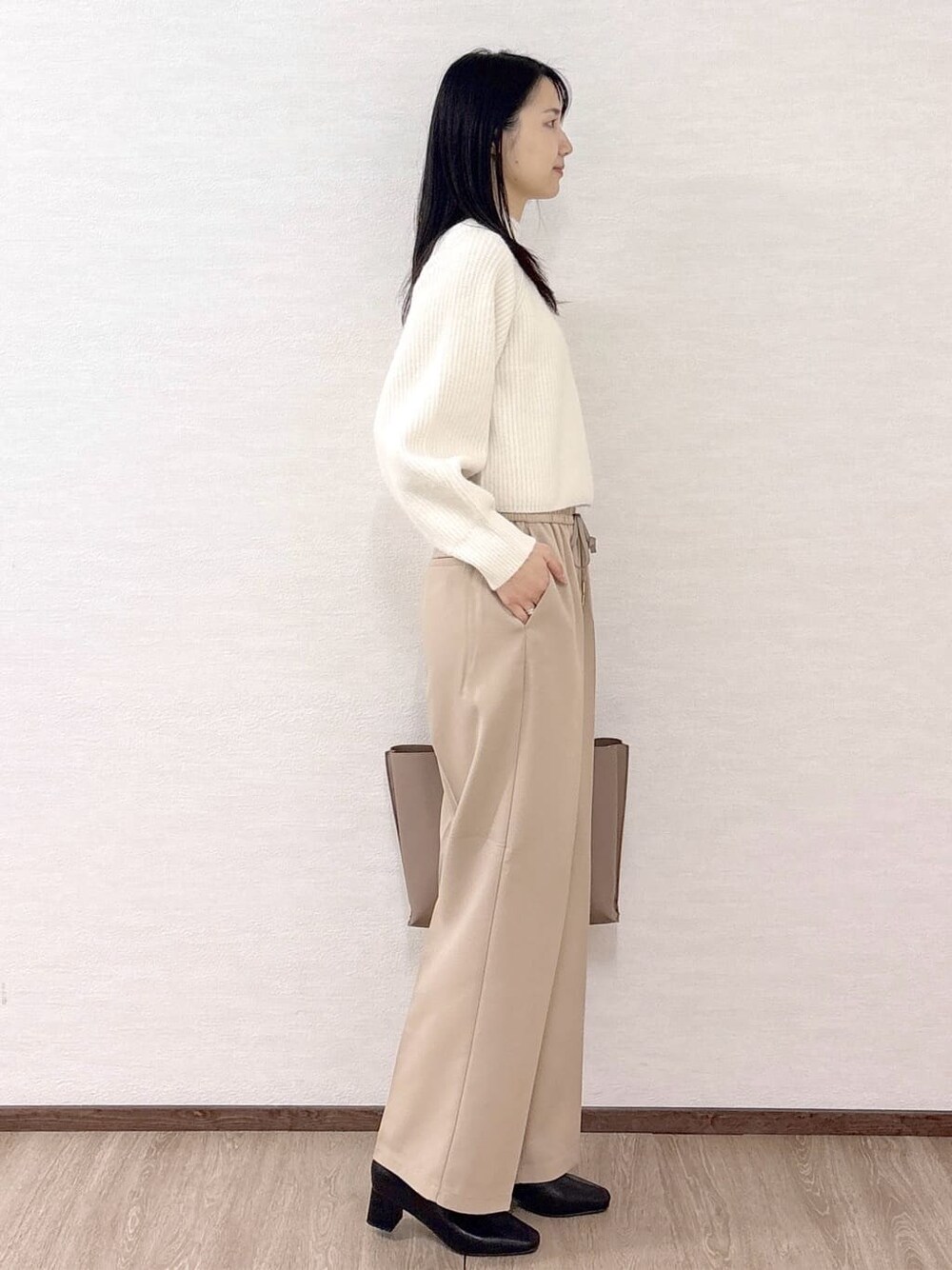 ホワイト系のニット/セーター、ベージュ系のその他パンツ、ベージュ系のトートバッグを着用したレディースの冬コーディネートの5枚目の写真