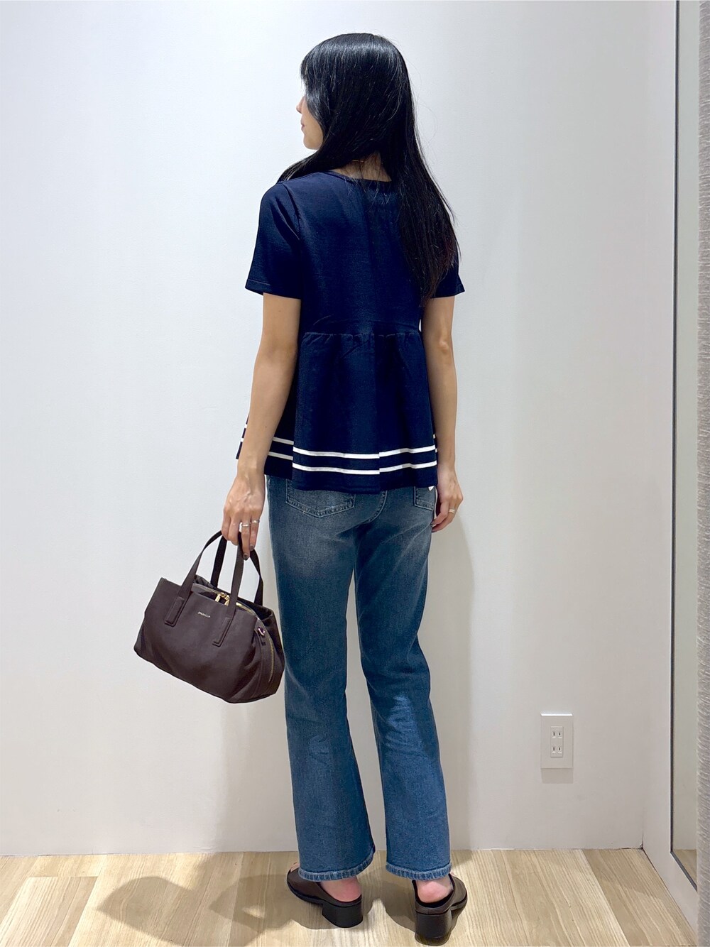 ブルー系のニット/セーター、ブルー系のデニムパンツ、ブラウン系のボストンバッグを着用したレディースの夏コーディネートの4枚目の写真