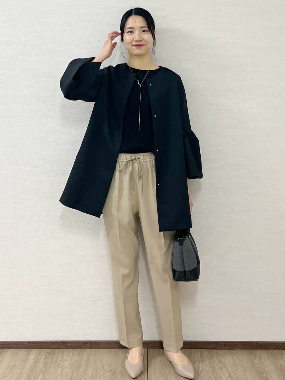 ブラック系のノーカラーコート、ブラック系のTシャツ/カットソー、ベージュ系のその他パンツを着用したレディースの冬コーディネートの4枚目の写真