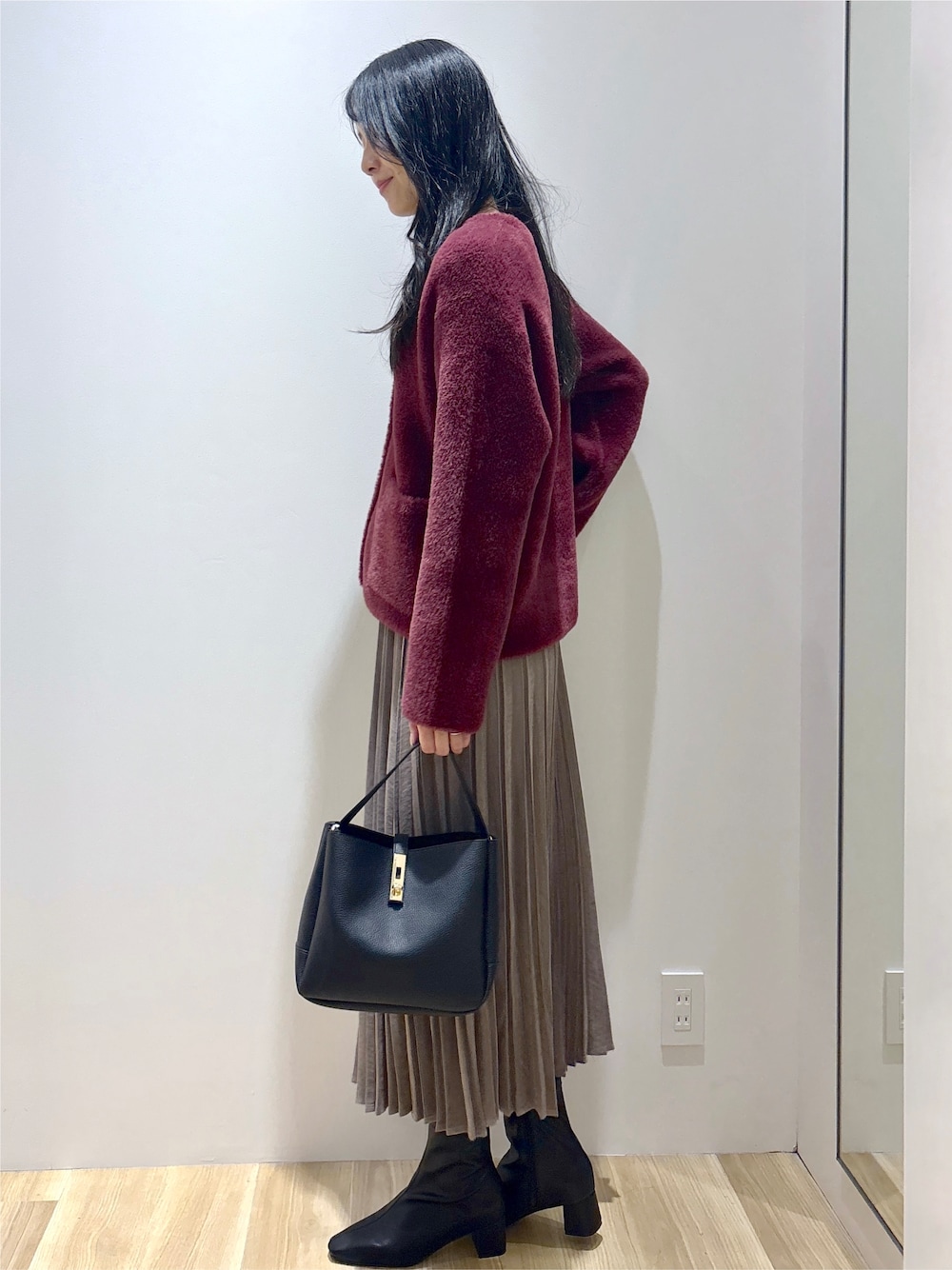 レッド系のカーディガン/ボレロ、ブラウン系のスカート、ブラック系のトートバッグを着用したレディースの秋コーディネートの3枚目の写真