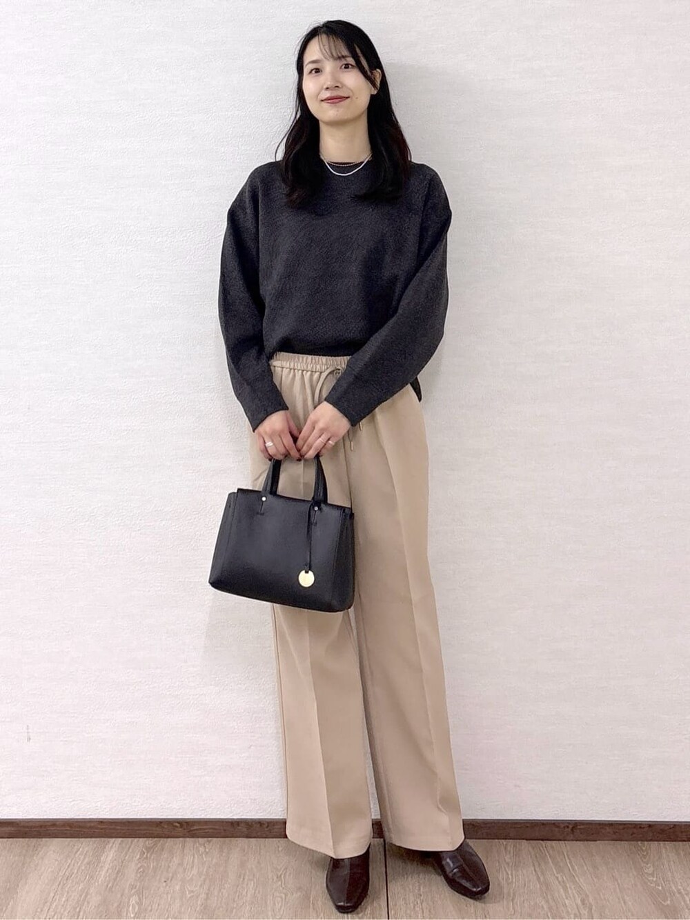 グレー系のニット/セーター、ベージュ系のその他パンツ、ブラック系のトートバッグを着用したレディースの冬コーディネートの2枚目の写真