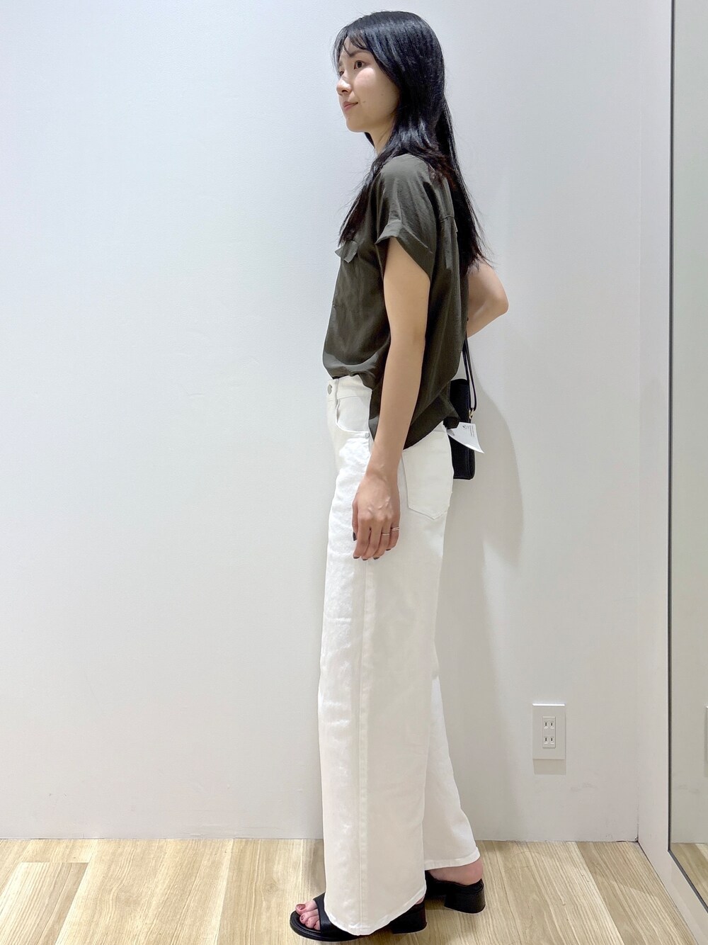 グリーン系のシャツ/ブラウス、ホワイト系のデニムパンツ、ブラック系のショルダーバッグを着用したレディースの夏コーディネートの3枚目の写真