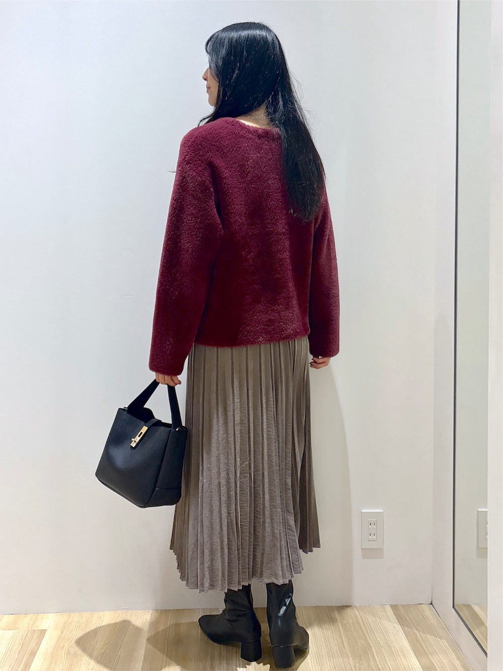 レッド系のカーディガン/ボレロ、ブラウン系のスカート、ブラック系のトートバッグを着用したレディースの秋コーディネートの4枚目の写真