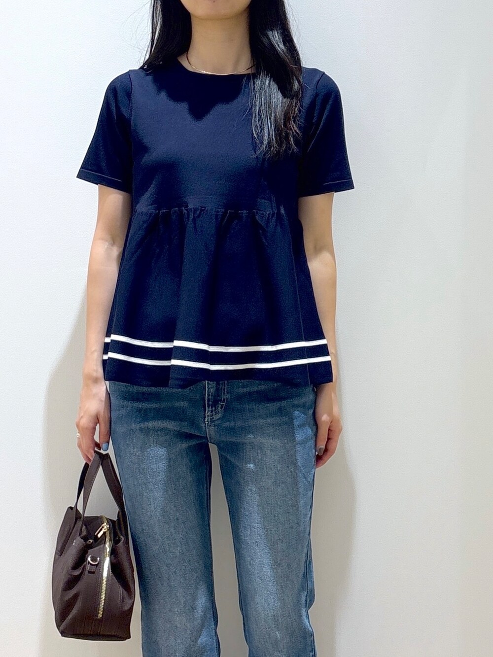 ブルー系のニット/セーター、ブルー系のデニムパンツ、ブラウン系のボストンバッグを着用したレディースの夏コーディネートの6枚目の写真