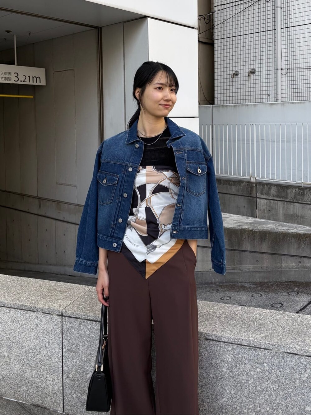 ブルー系のデニムジャケット、ブラック系のニット/セーター、ブラック系のショルダーバッグを着用したレディースの春コーディネートの7枚目の写真