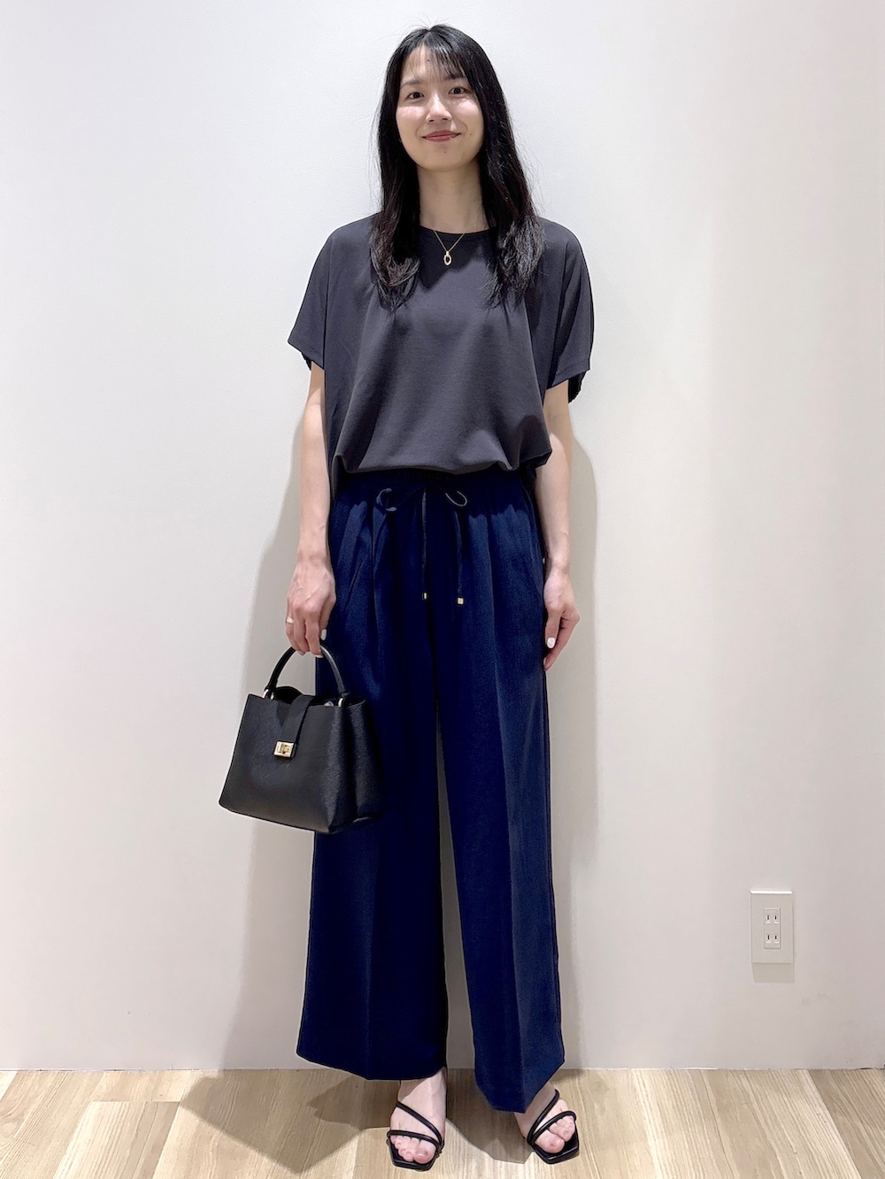 ブラック系のハンドバッグ、ベージュ系のショルダーバッグ、グレー系のTシャツ/カットソーを着用したレディースの春コーディネートの2枚目の写真
