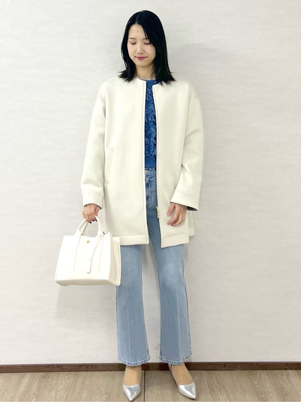 ホワイト系のノーカラーコート、ブルー系のニット/セーター、ブルー系のデニムパンツを着用したレディースの冬コーディネートの10枚目の写真