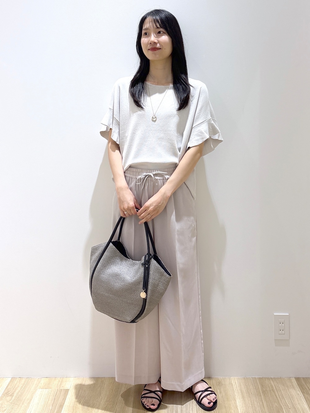 ベージュ系のその他パンツ、ブラック系のサンダル、グレー系のトートバッグを着用したレディースの春コーディネートの9枚目の写真