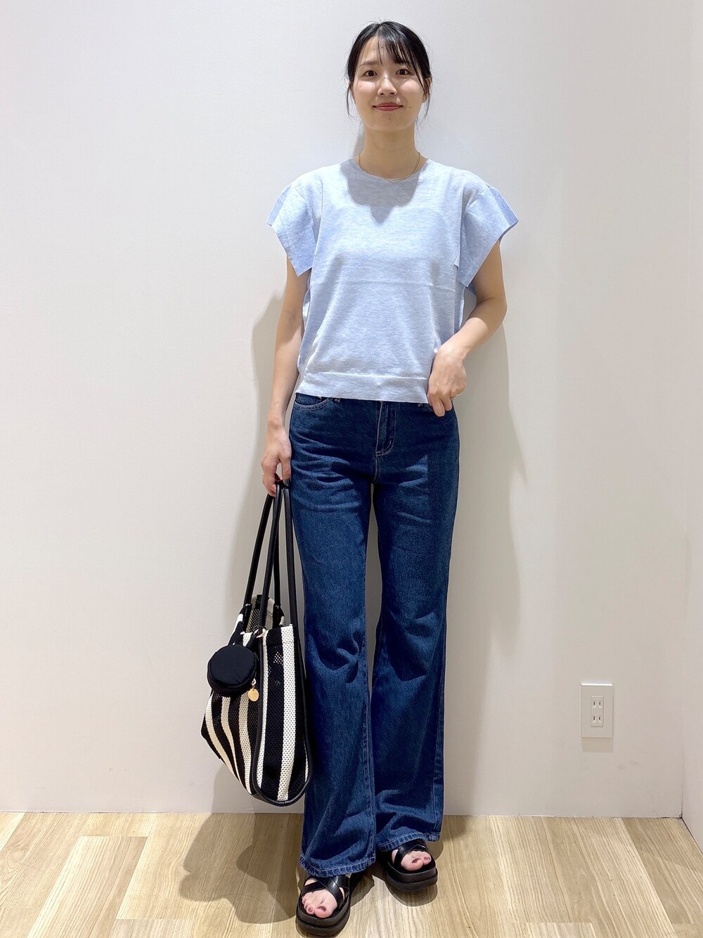 ブルー系のニット/セーター、ブルー系のデニムパンツ、ブラック系のトートバッグを着用したレディースの夏コーディネートの8枚目の写真