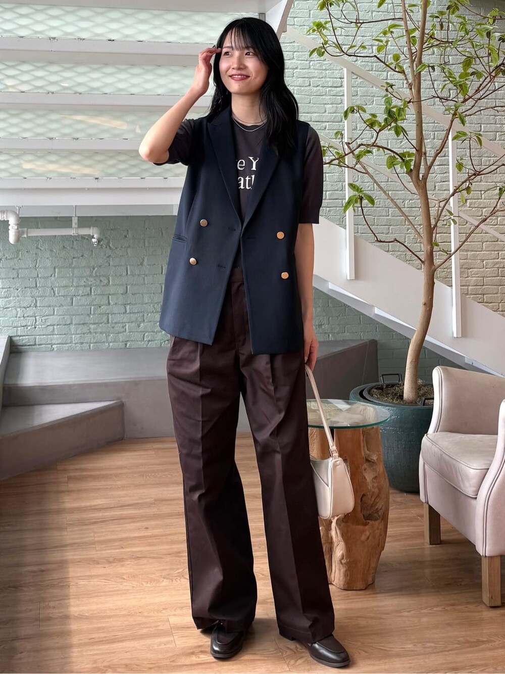 グレー系のニット/セーター、ブラウン系のその他パンツ、ホワイト系のショルダーバッグを着用したレディースの春コーディネートの8枚目の写真