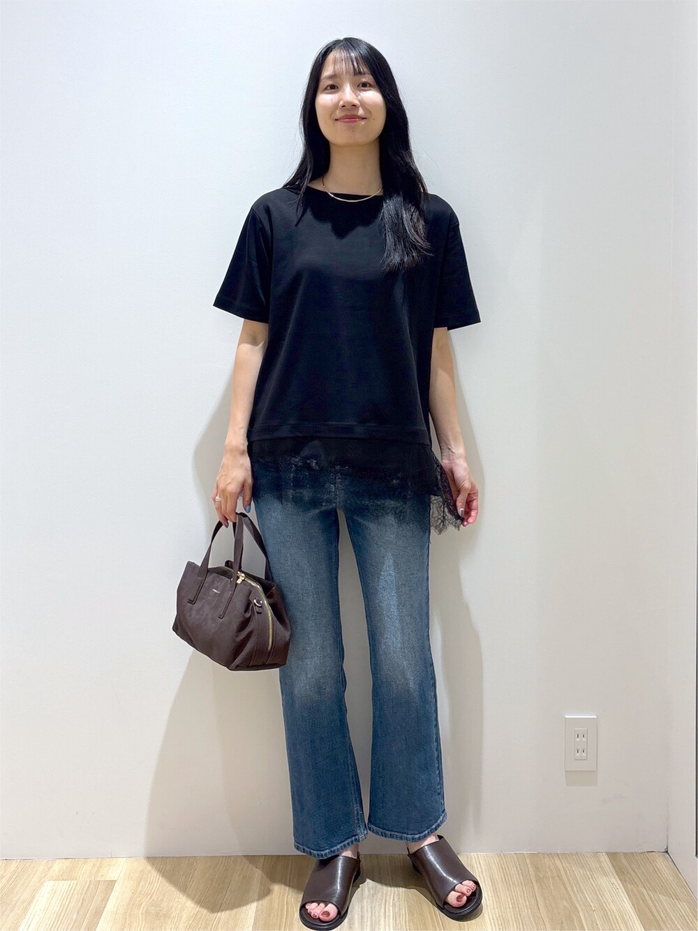 ブラック系のTシャツ/カットソー、ブルー系のデニムパンツ、ブラウン系のボストンバッグを着用したレディースの夏コーディネートの2枚目の写真