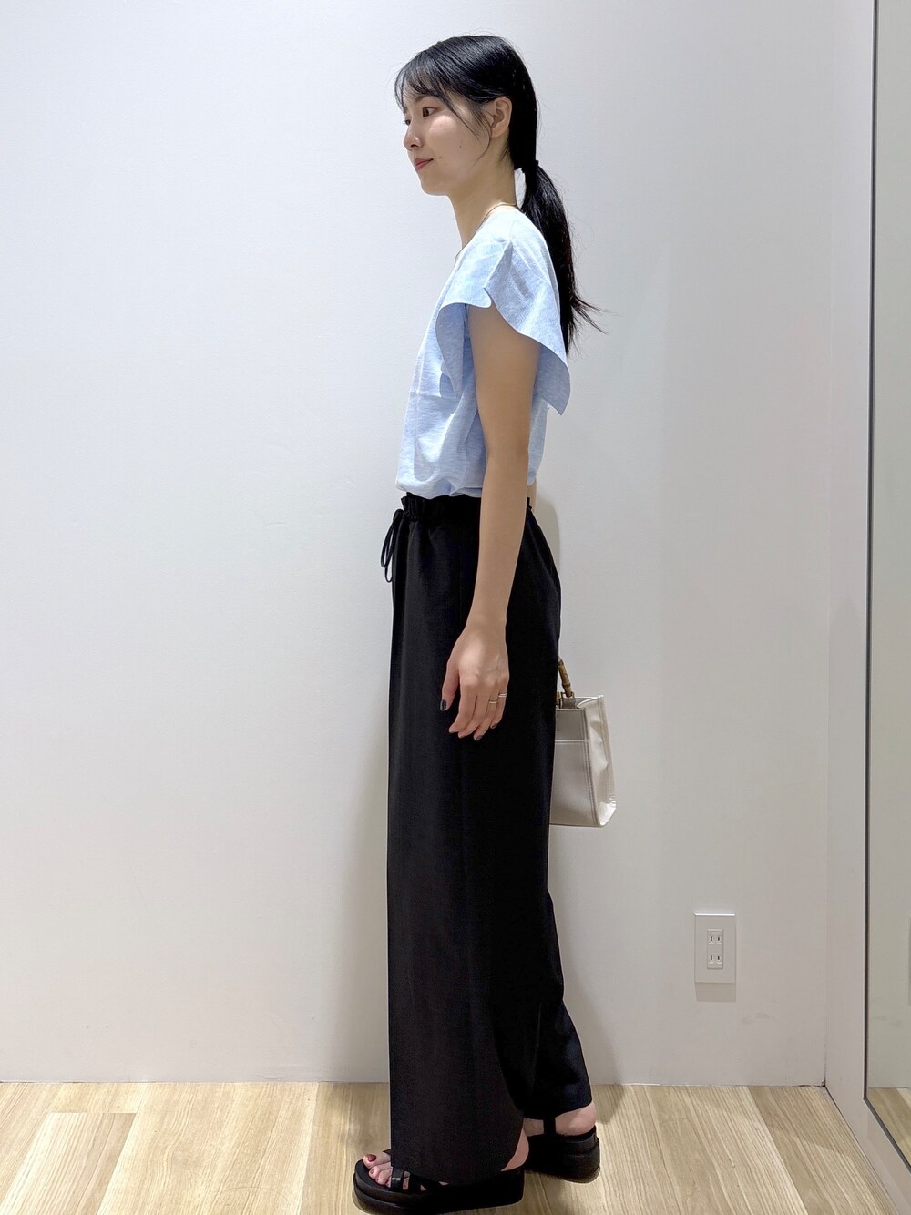 ブルー系のニット/セーター、グレー系のその他パンツ、ホワイト系のトートバッグを着用したレディースの夏コーディネートの3枚目の写真