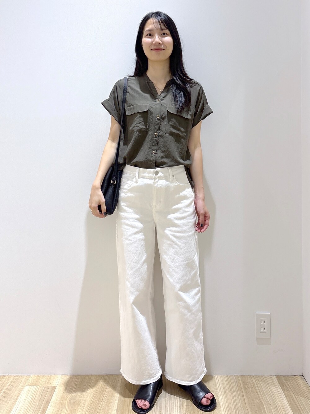 グリーン系のシャツ/ブラウス、ホワイト系のデニムパンツ、ブラック系のショルダーバッグを着用したレディースの夏コーディネートの2枚目の写真