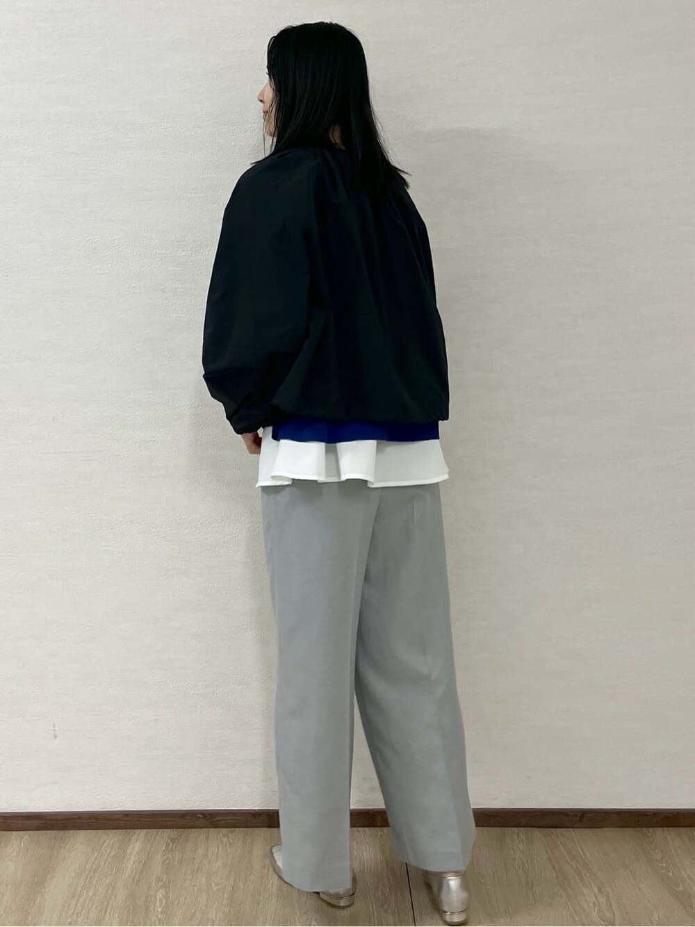 ブラック系のノーカラーコート、ブルー系のニット/セーター、グレー系のその他パンツを着用したレディースの春コーディネートの5枚目の写真