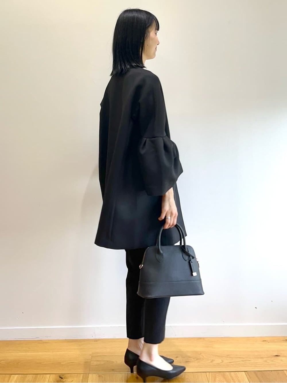 ブラック系のノーカラーコート、ホワイト系のシャツ/ブラウス、ブラック系のその他パンツを着用したレディースの秋コーディネートの5枚目の写真