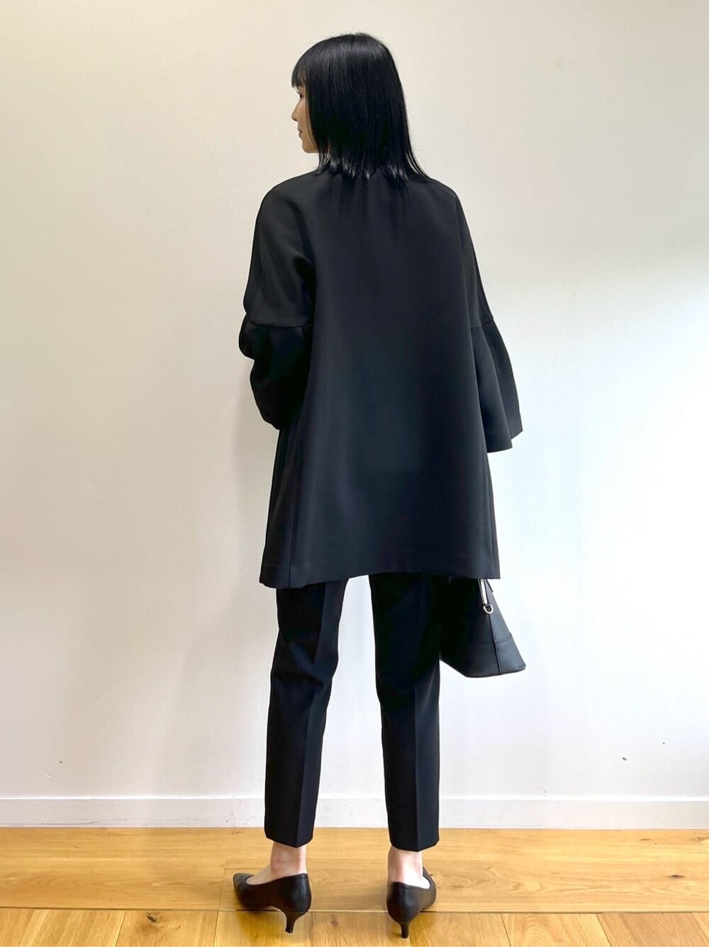 ブラック系のノーカラーコート、ホワイト系のシャツ/ブラウス、ブラック系のその他パンツを着用したレディースの秋コーディネートの4枚目の写真