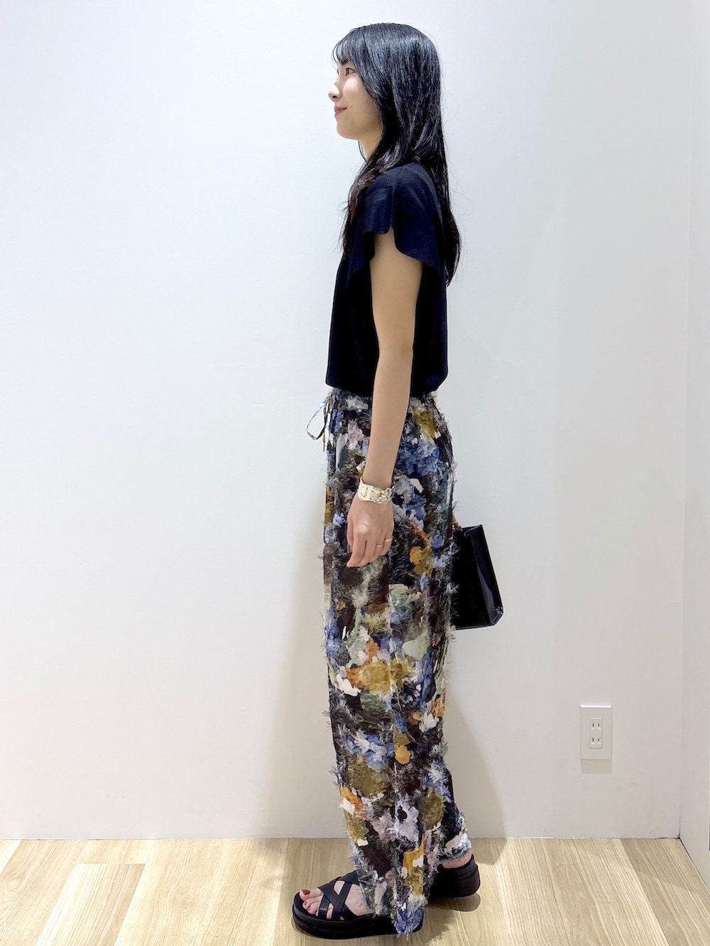 ブラック系のニット/セーター、ブラウン系のその他パンツ、ブラック系のトートバッグを着用したレディースの夏コーディネートの3枚目の写真