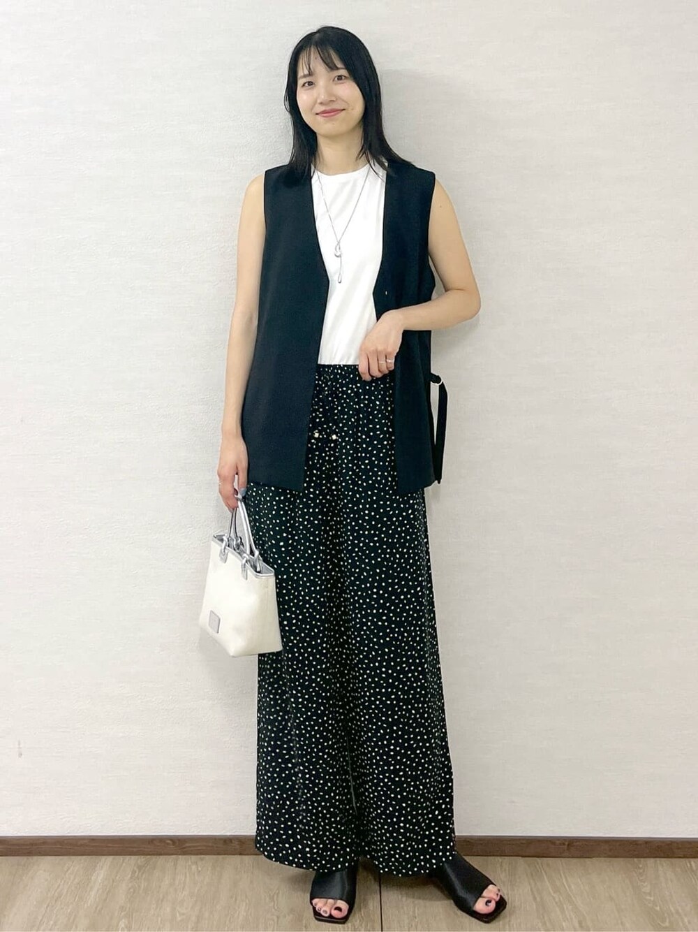 ブラック系のベスト、ホワイト系のタンクトップ、ブラック系のその他パンツを着用したレディースの夏コーディネートの3枚目の写真