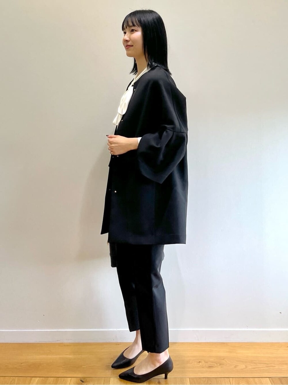 ブラック系のノーカラーコート、ホワイト系のシャツ/ブラウス、ブラック系のその他パンツを着用したレディースの秋コーディネートの2枚目の写真