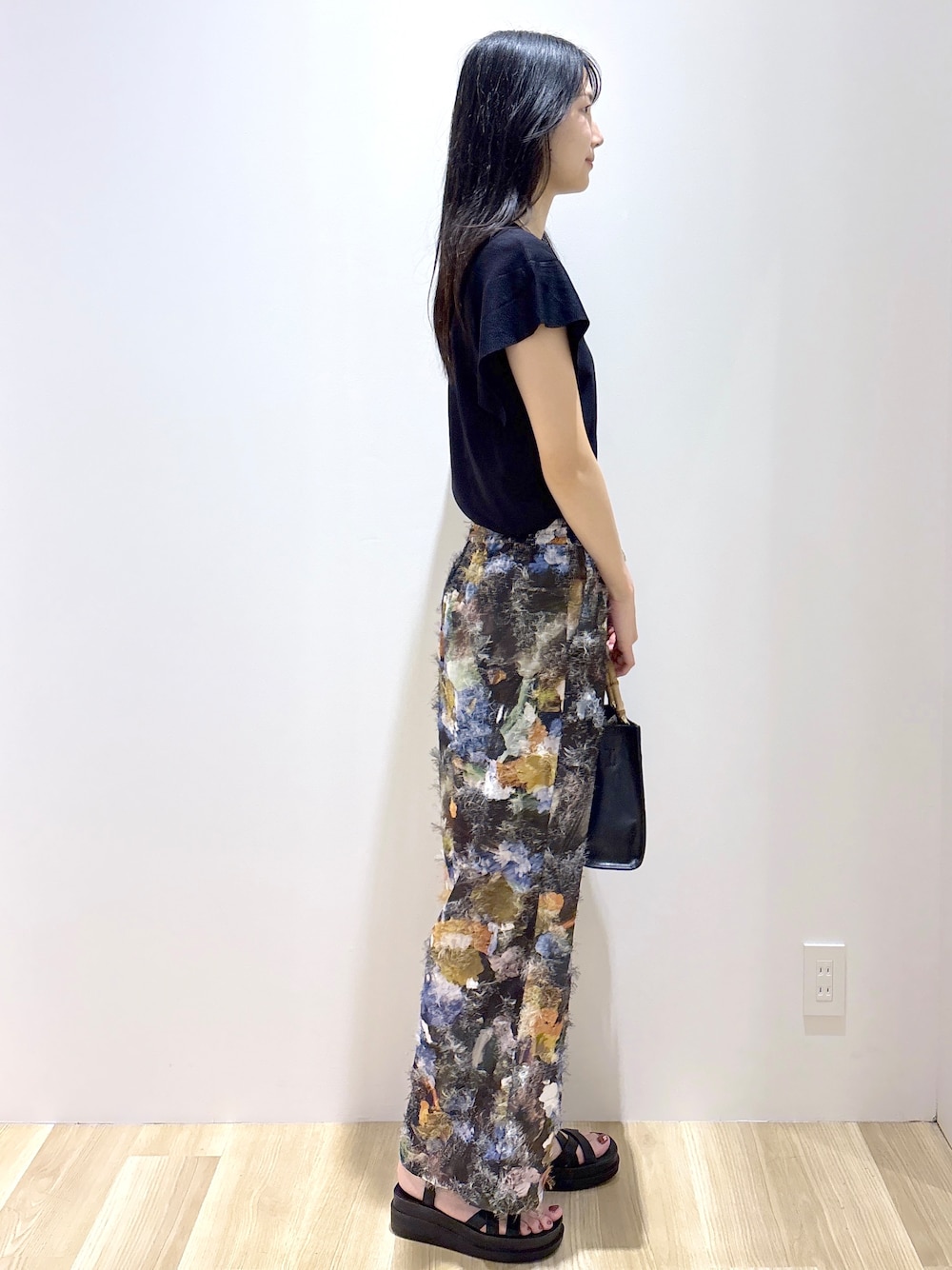ブラック系のニット/セーター、ブラウン系のその他パンツ、ブラック系のトートバッグを着用したレディースの夏コーディネートの5枚目の写真