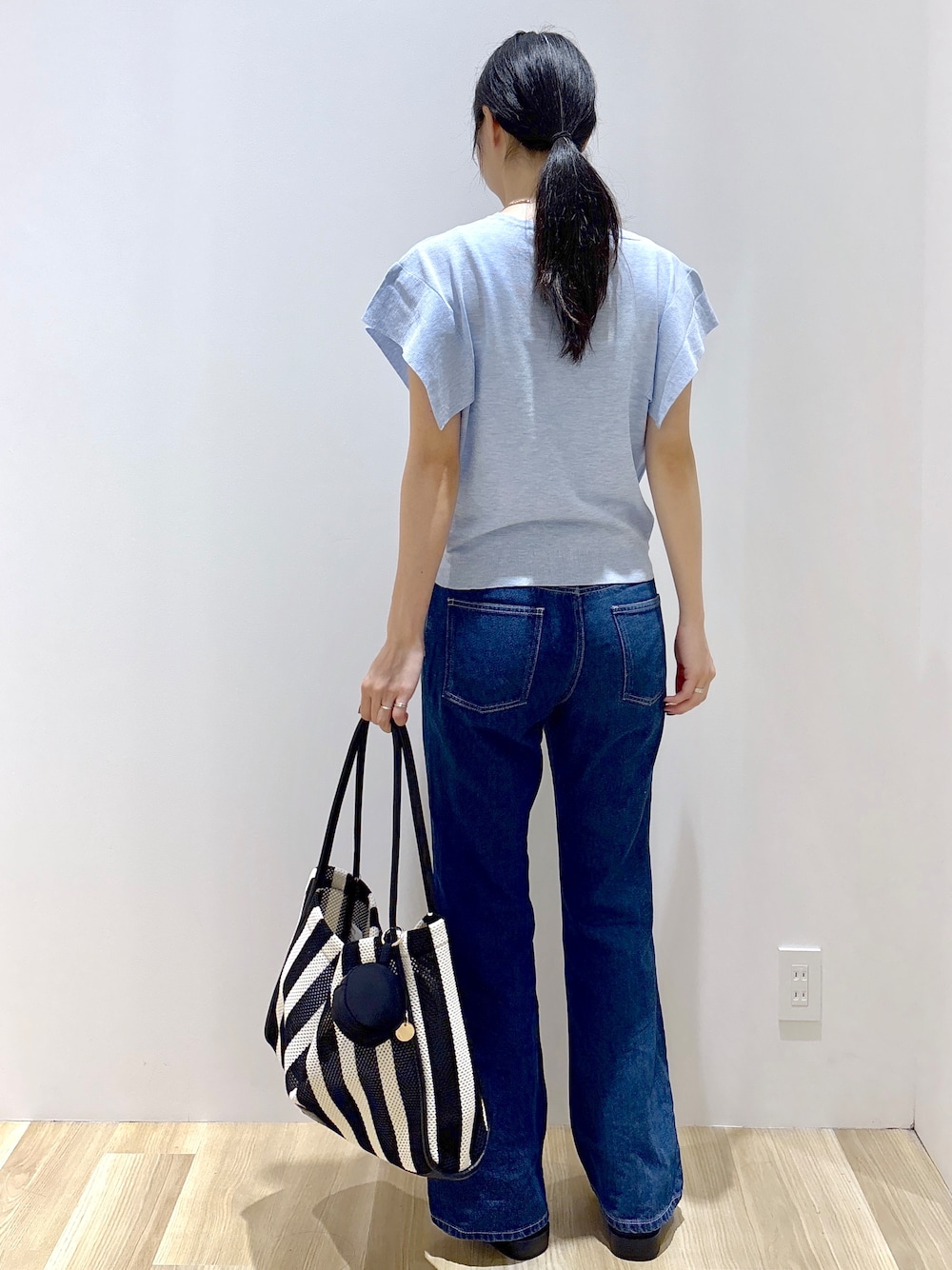 ブルー系のニット/セーター、ブルー系のデニムパンツ、ブラック系のトートバッグを着用したレディースの夏コーディネートの4枚目の写真