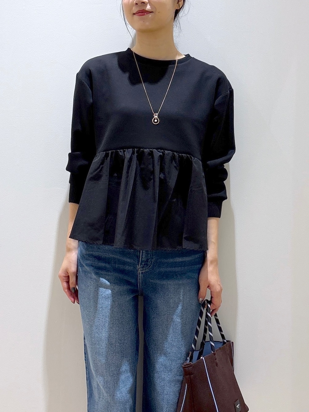 ブラック系のTシャツ/カットソー、ブルー系のデニムパンツ、ブラウン系のトートバッグを着用したレディースの秋コーディネートの6枚目の写真