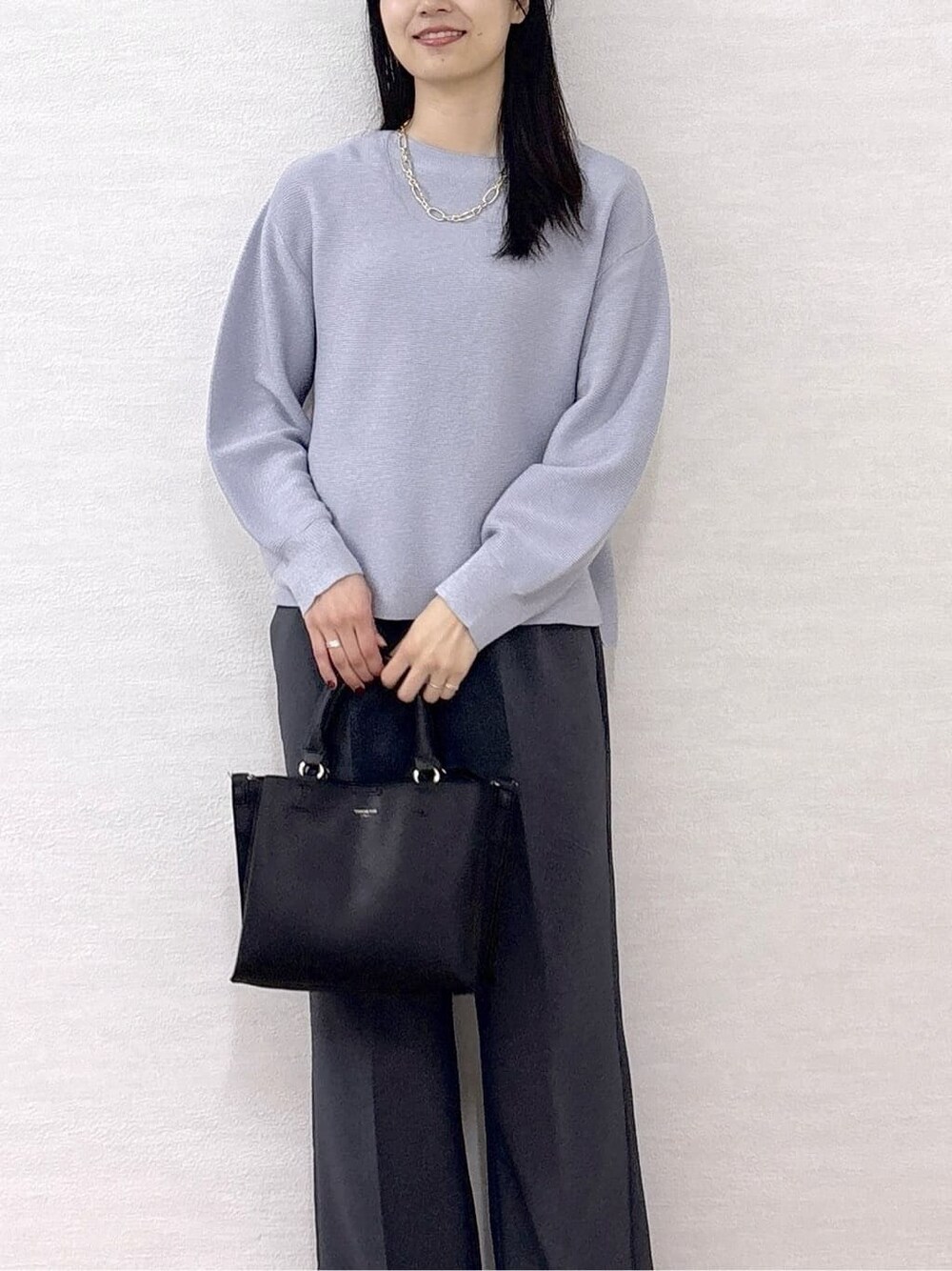 ブルー系のニット/セーター、グレー系のその他パンツ、ブラック系のトートバッグを着用したレディースの冬コーディネートの6枚目の写真