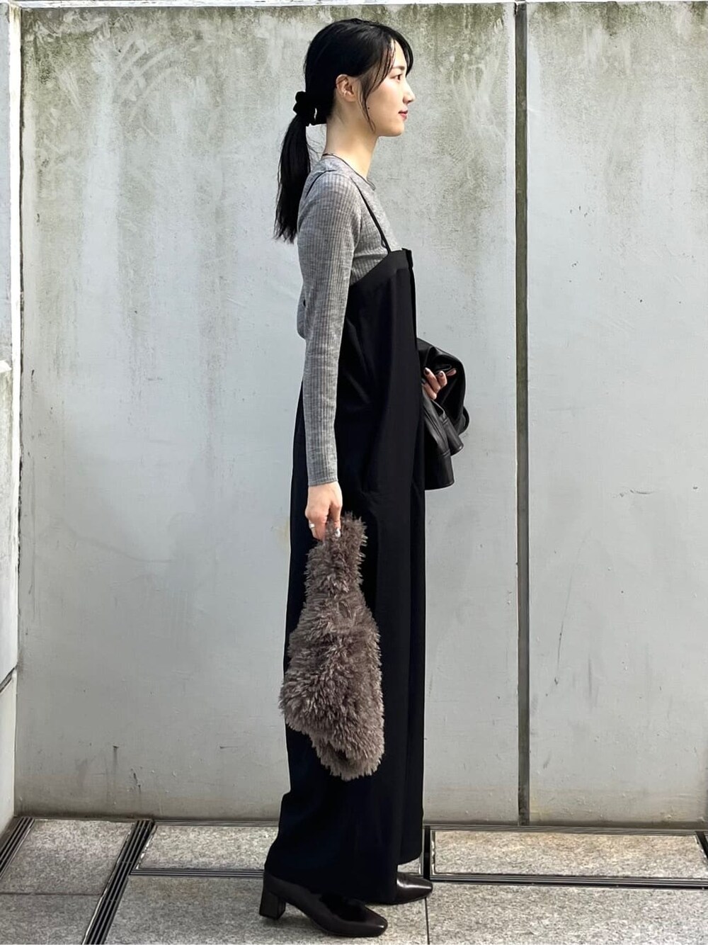 グレー系のニット/セーター、ブラック系のサロペット/オーバーオール、ブラウン系のハンドバッグを着用したレディースの秋コーディネートの4枚目の写真