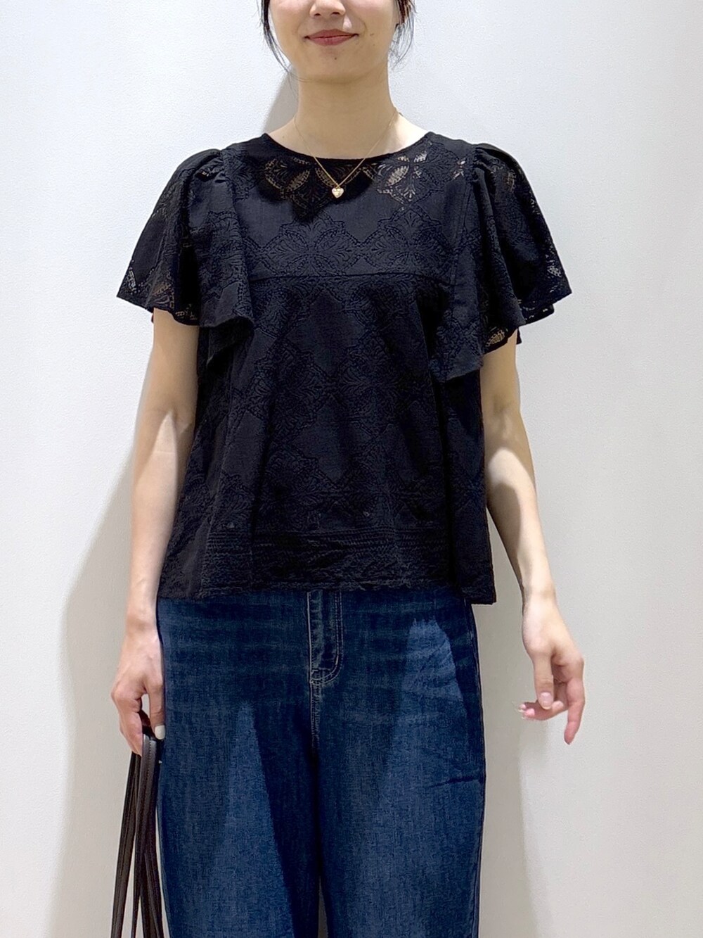 ブラック系のシャツ/ブラウス、ブルー系のデニムパンツ、ベージュ系のトートバッグを着用したレディースの春コーディネートの6枚目の写真
