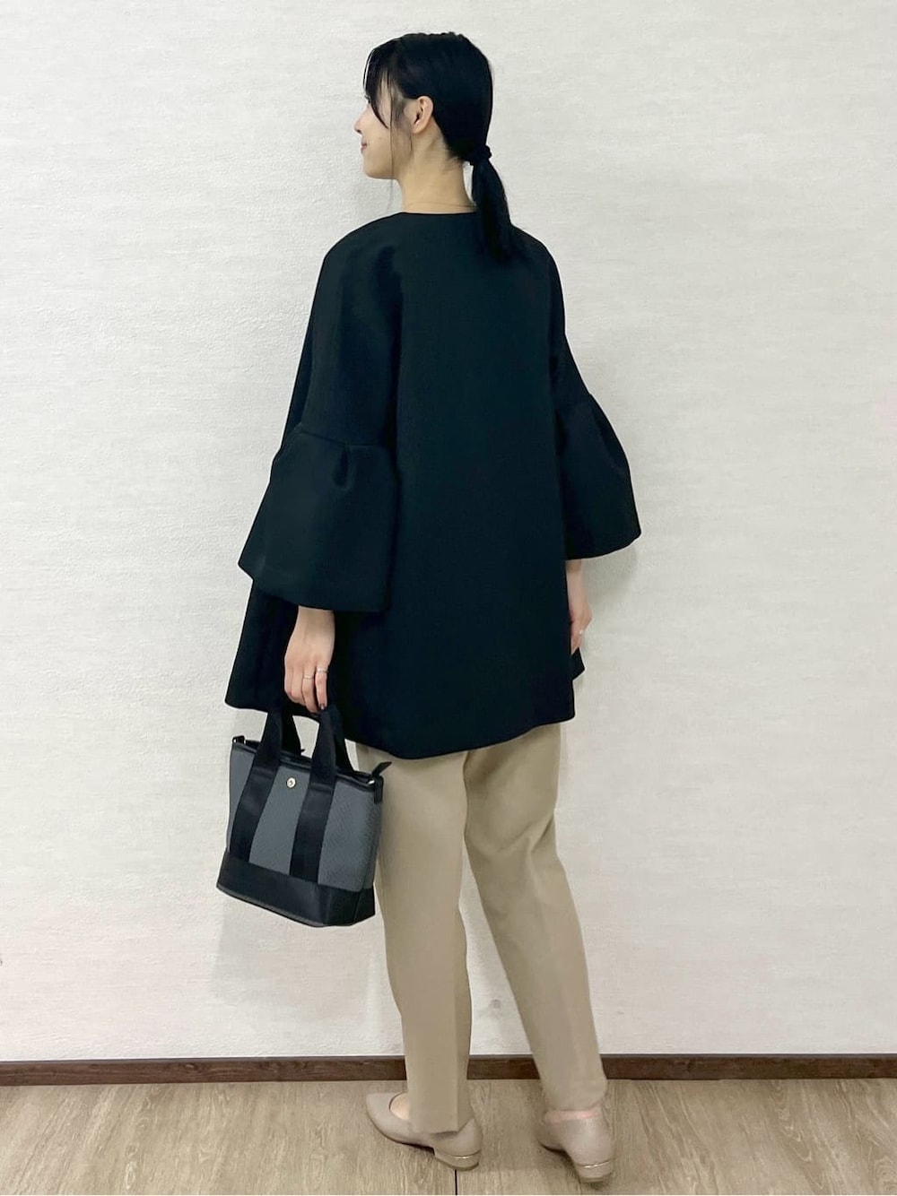 ブラック系のノーカラーコート、ブラック系のTシャツ/カットソー、ベージュ系のその他パンツを着用したレディースの冬コーディネートの6枚目の写真