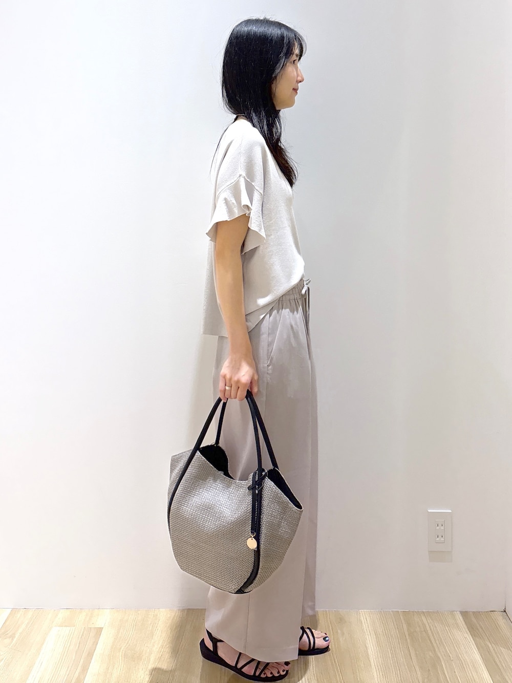 ベージュ系のその他パンツ、ブラック系のサンダル、グレー系のトートバッグを着用したレディースの春コーディネートの5枚目の写真