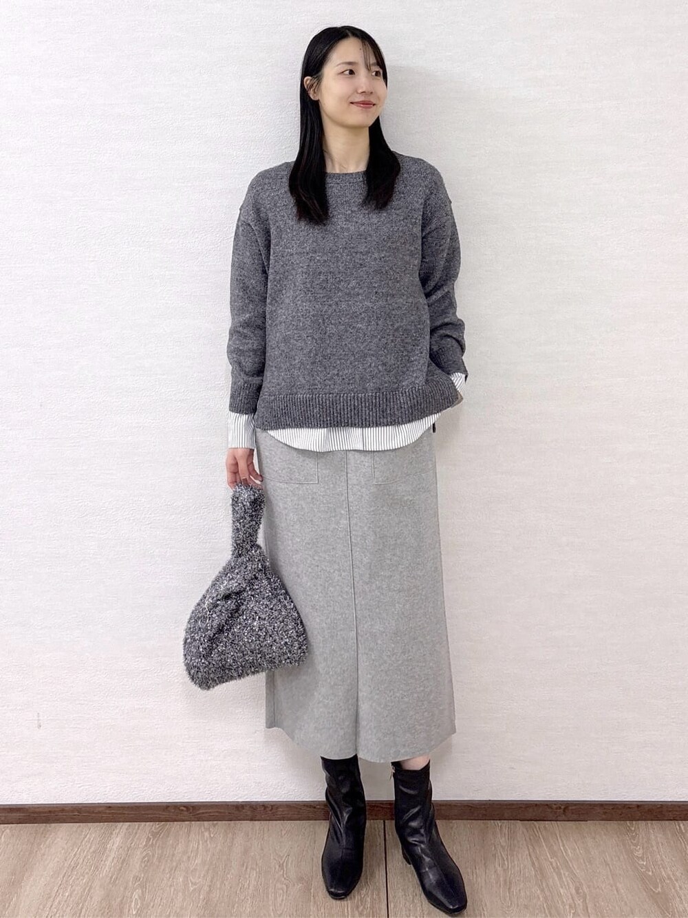 ブラック系のノーカラーコート、グレー系のニット/セーター、ホワイト系のTシャツ/カットソーを着用したレディースの冬コーディネートの7枚目の写真