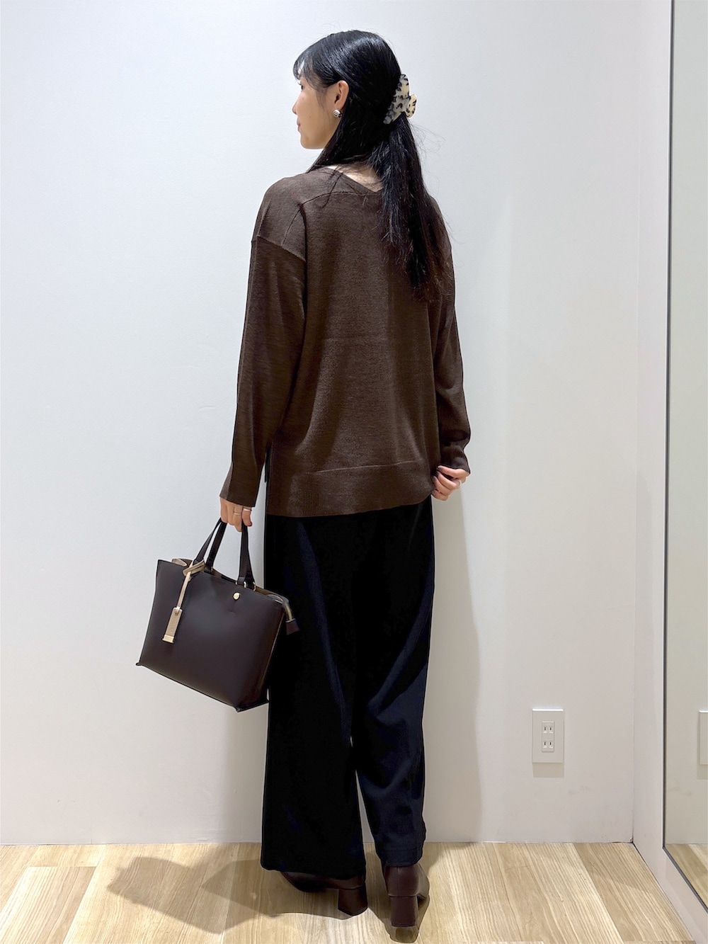 ブラウン系のニット/セーター、ブラック系のその他パンツ、ブラウン系のトートバッグを着用したレディースの秋コーディネートの4枚目の写真
