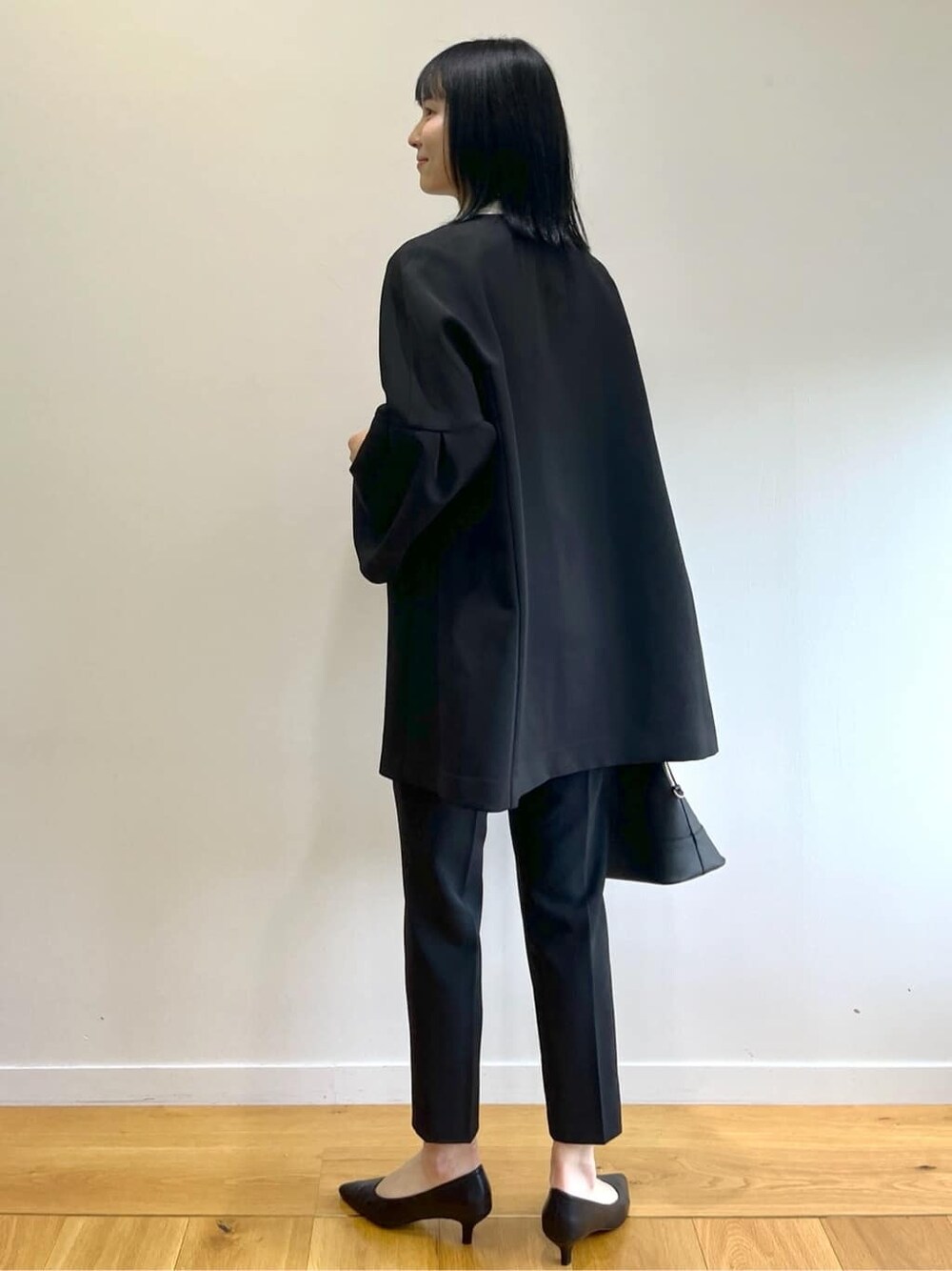 ブラック系のノーカラーコート、ホワイト系のシャツ/ブラウス、ブラック系のその他パンツを着用したレディースの秋コーディネートの3枚目の写真
