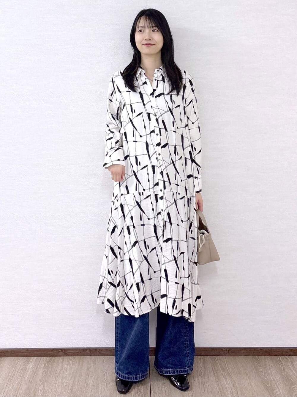 ブルー系のデニムパンツ、ブラック系のパンプス、ベージュ系のショルダーバッグを着用したレディースの春コーディネートの2枚目の写真