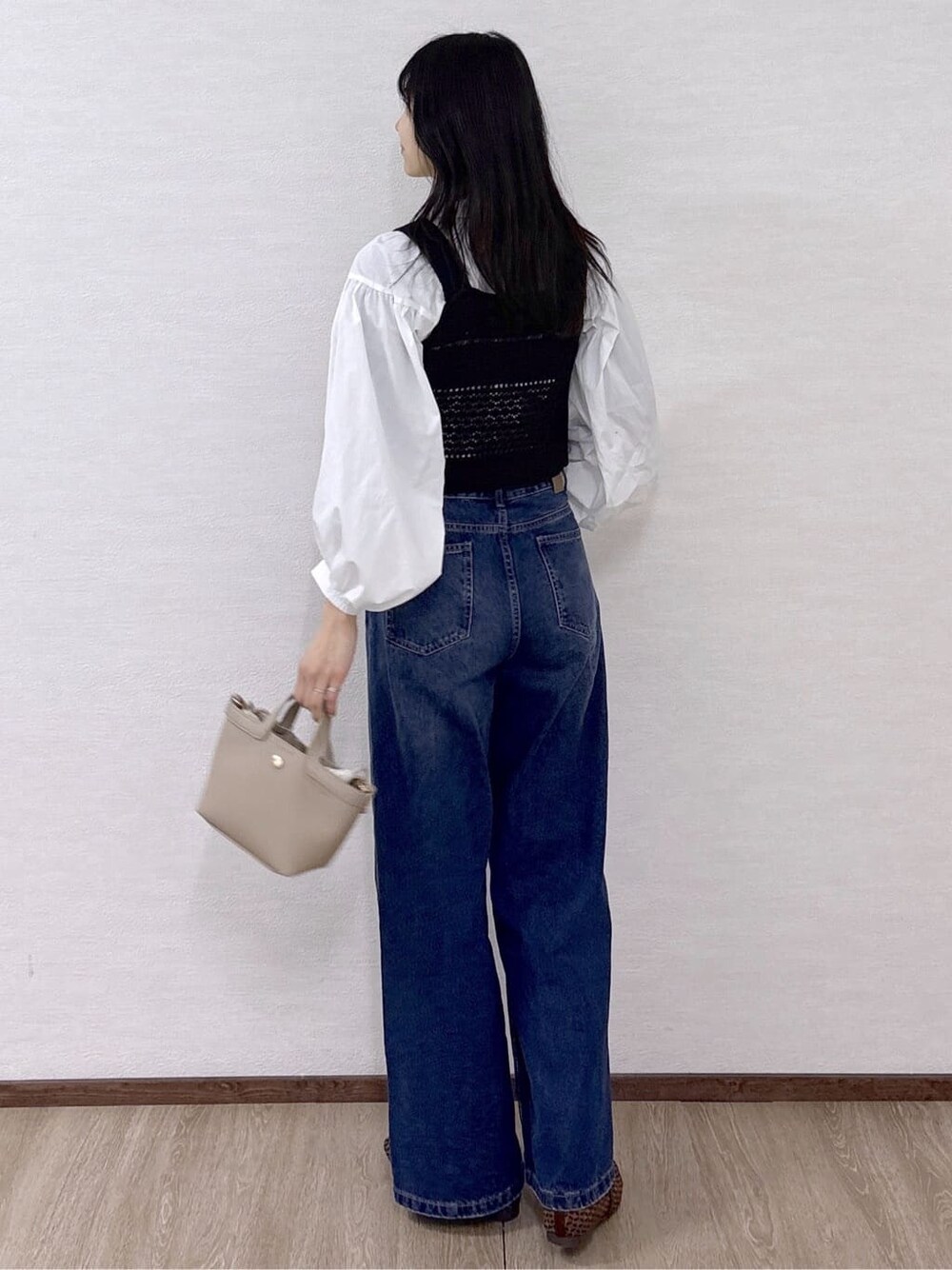 ブラック系のニット/セーター、ホワイト系のシャツ/ブラウス、ブルー系のデニムパンツを着用したレディースの春コーディネートの4枚目の写真
