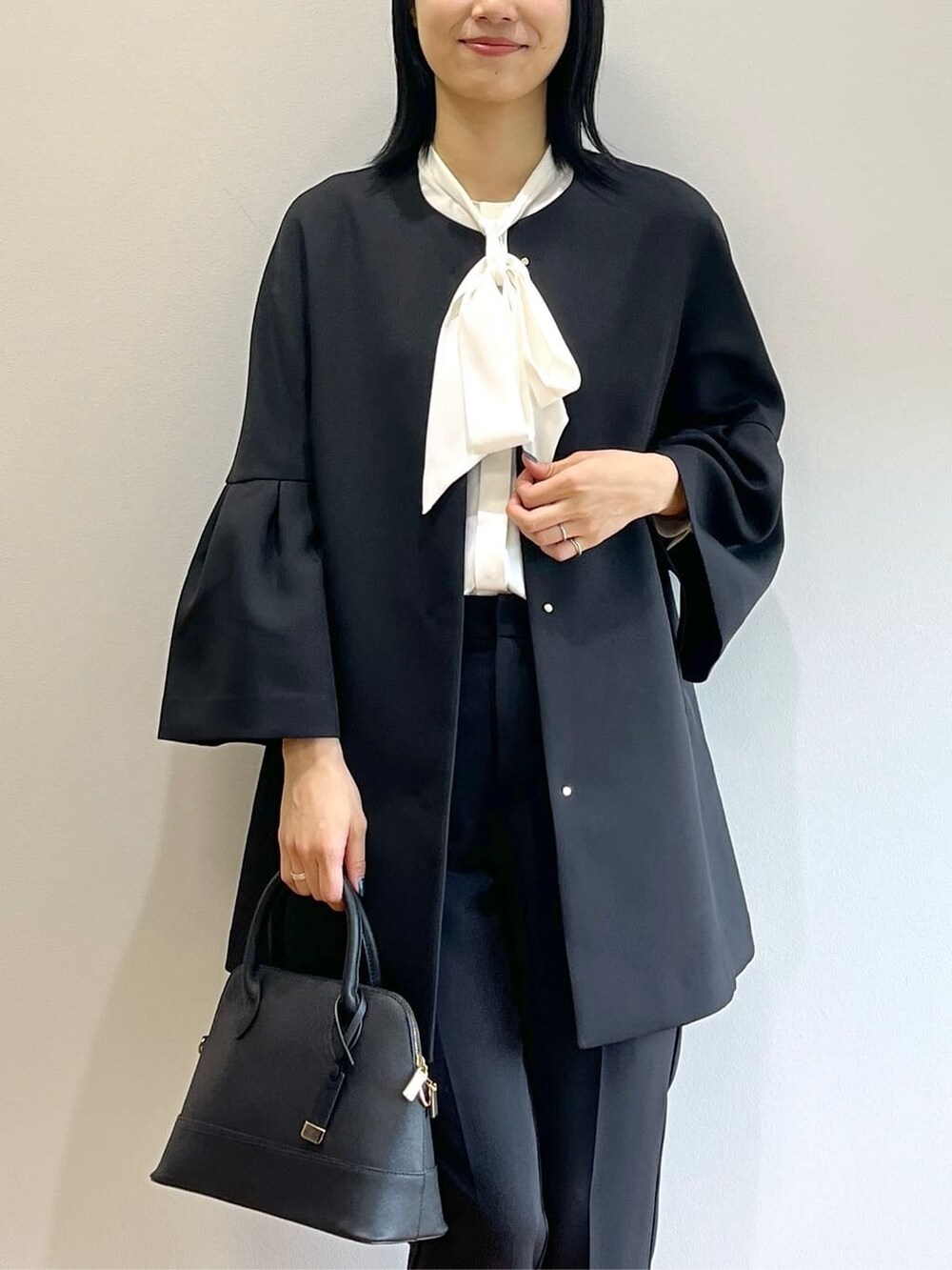 ブラック系のノーカラーコート、ホワイト系のシャツ/ブラウス、ブラック系のその他パンツを着用したレディースの秋コーディネートの6枚目の写真