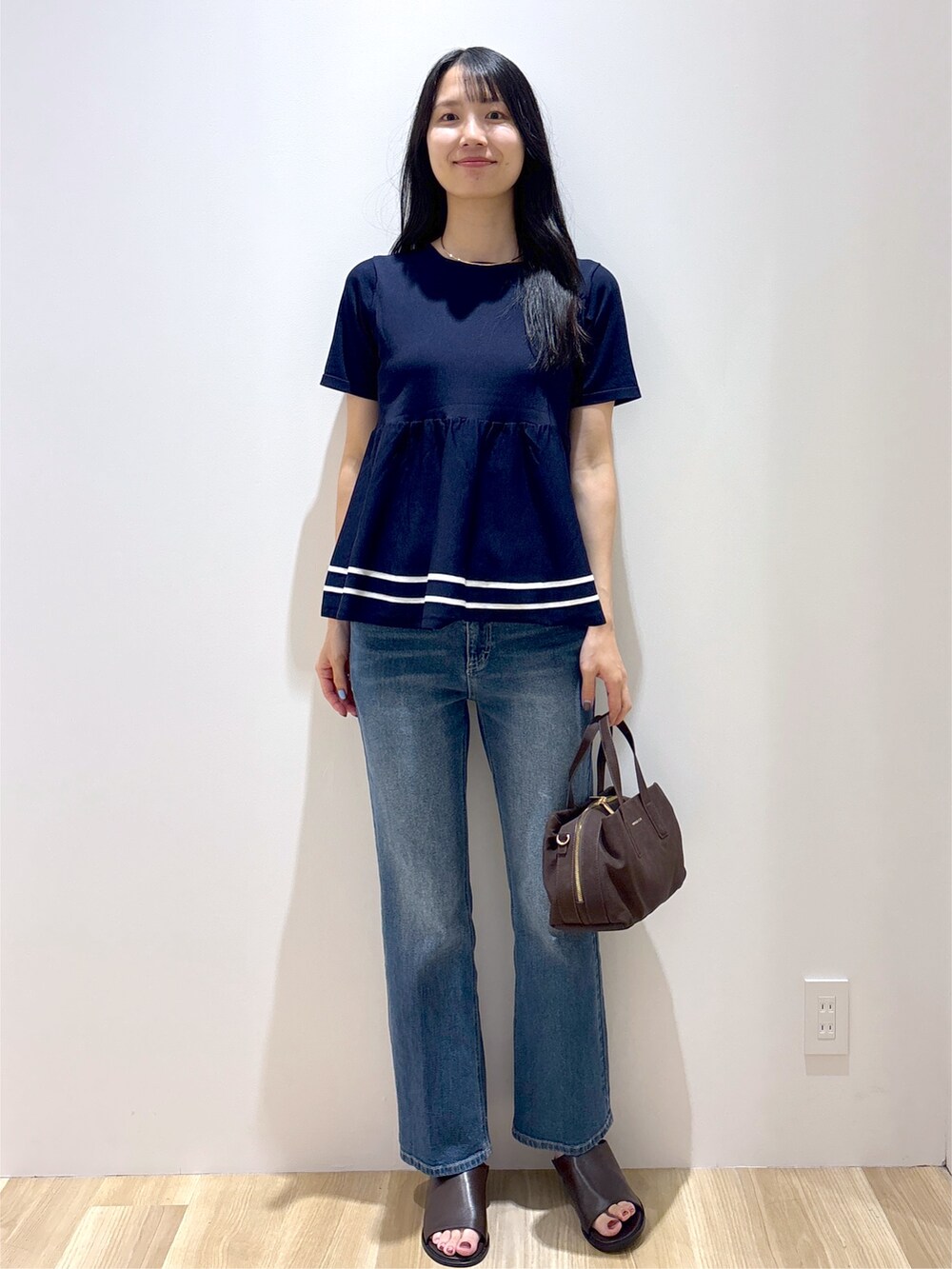 ブルー系のニット/セーター、ブルー系のデニムパンツ、ブラウン系のボストンバッグを着用したレディースの夏コーディネートの10枚目の写真