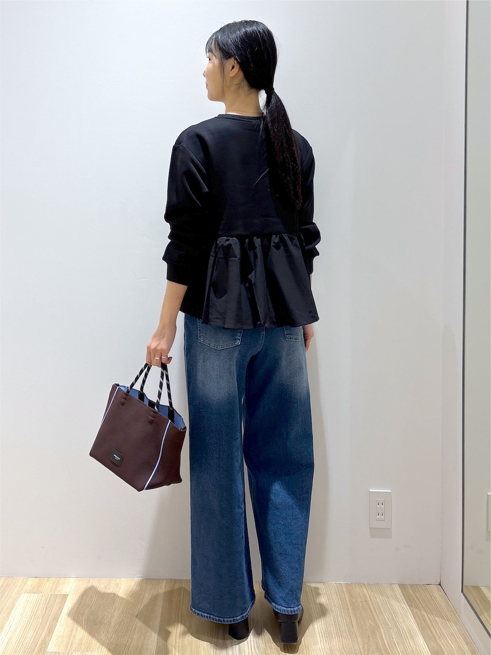 ブラック系のTシャツ/カットソー、ブルー系のデニムパンツ、ブラウン系のトートバッグを着用したレディースの秋コーディネートの4枚目の写真