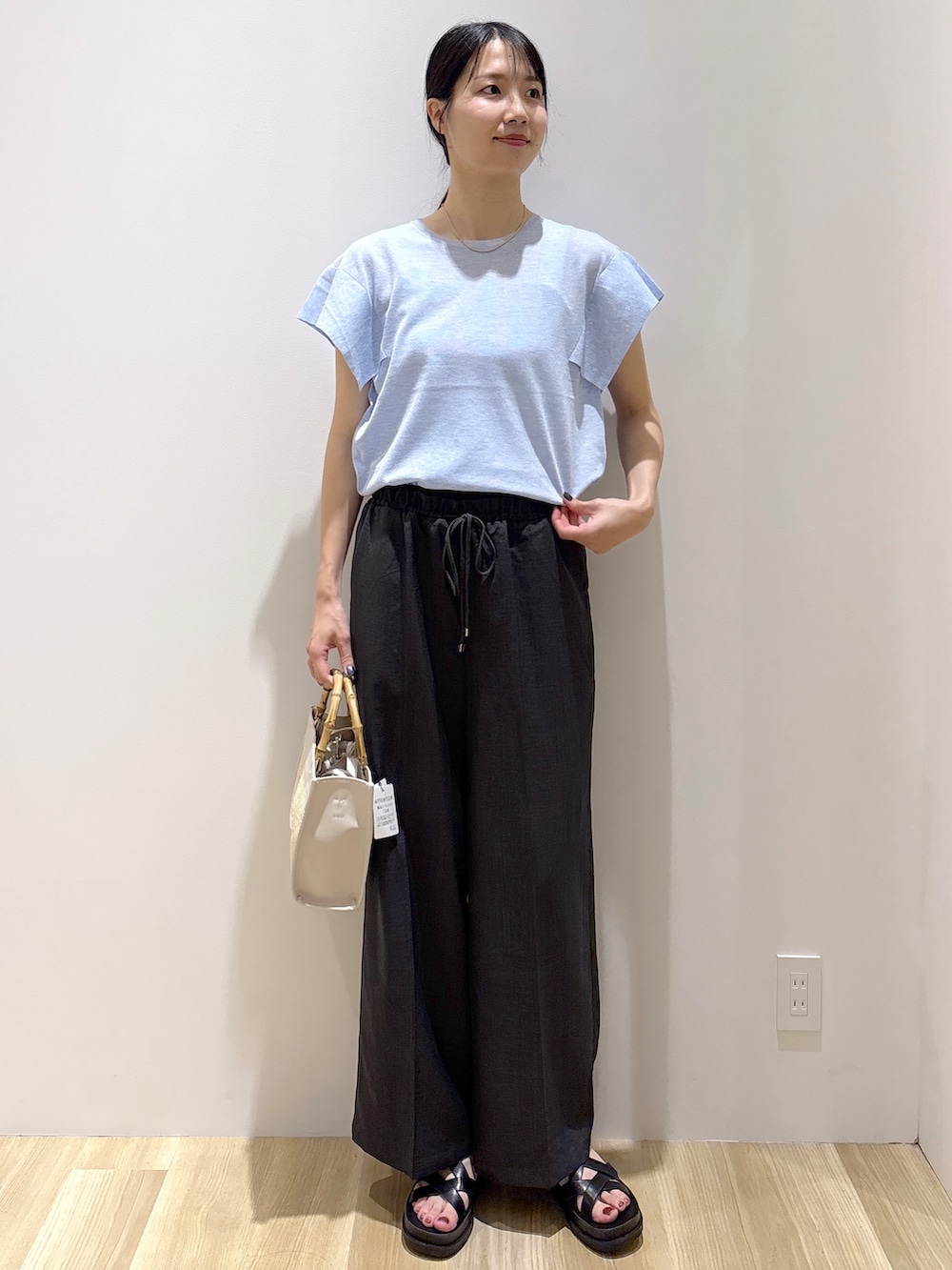 ブルー系のニット/セーター、グレー系のその他パンツ、ホワイト系のトートバッグを着用したレディースの夏コーディネートの2枚目の写真