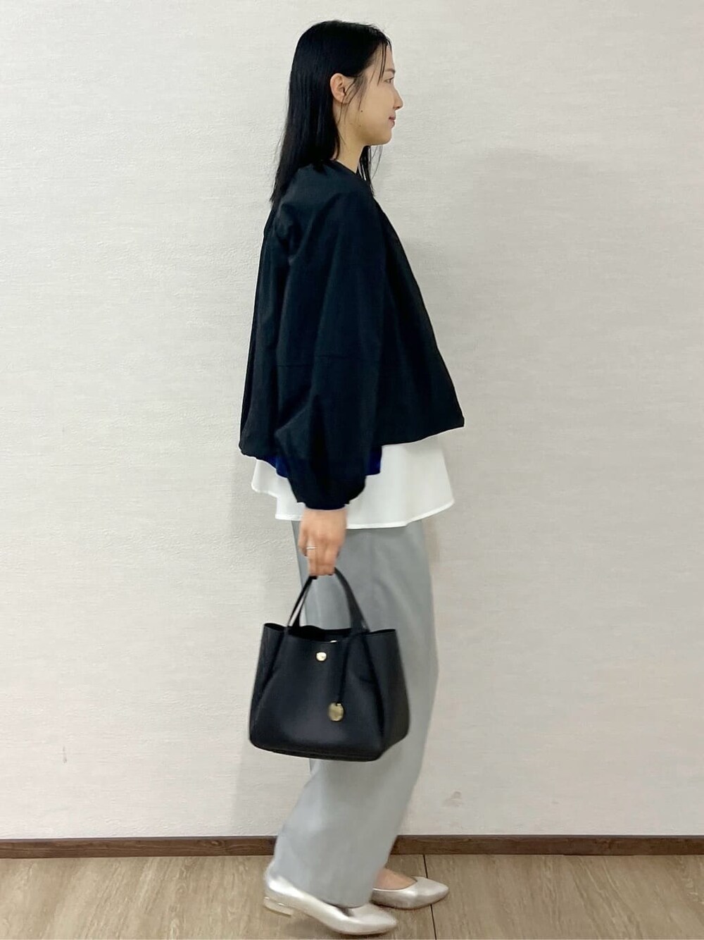ブラック系のノーカラーコート、ブルー系のニット/セーター、グレー系のその他パンツを着用したレディースの春コーディネートの6枚目の写真