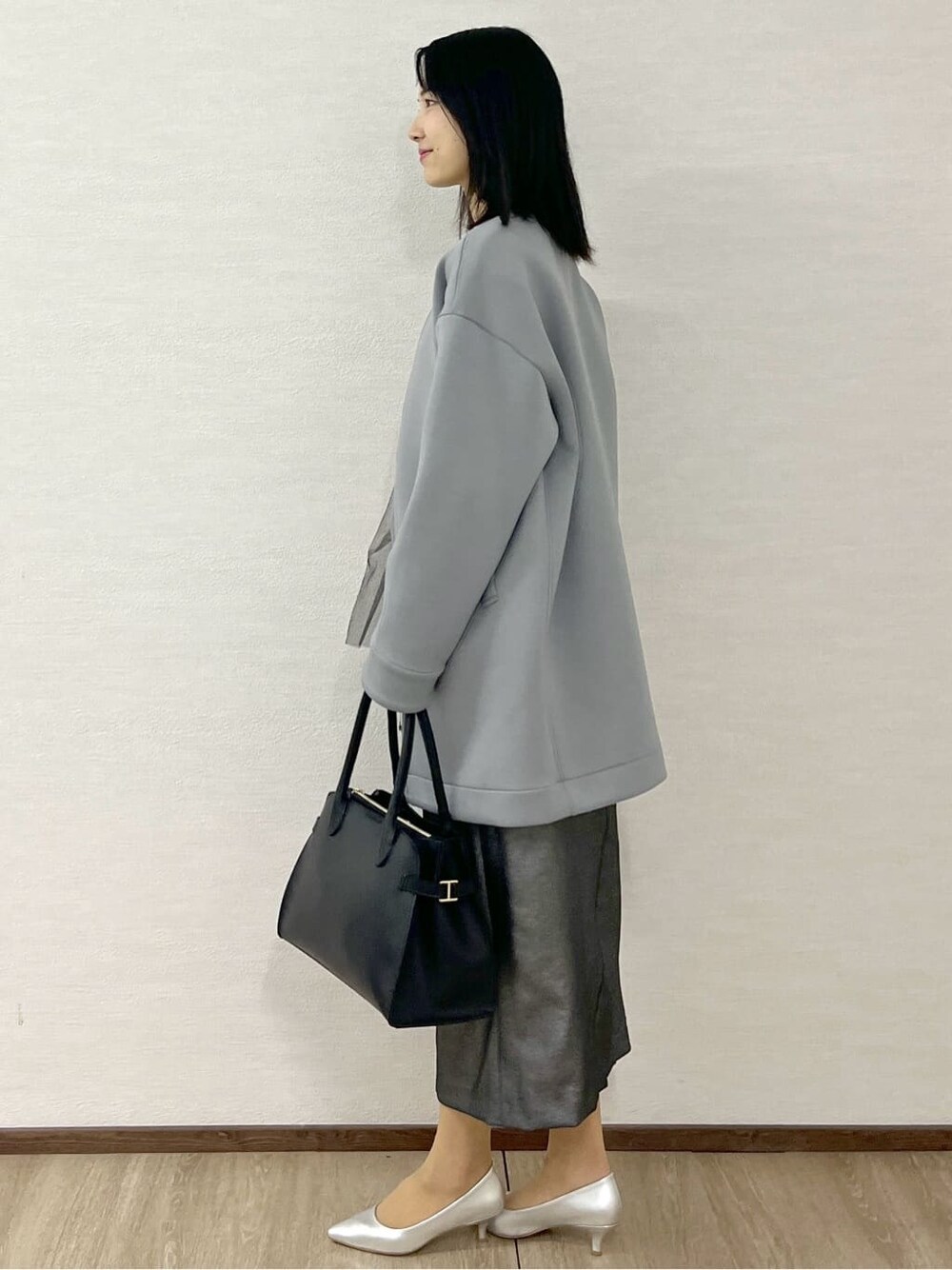 グレー系のノーカラーコート、ブラック系のTシャツ/カットソー、ブラック系のスカートを着用したレディースの冬コーディネートの4枚目の写真