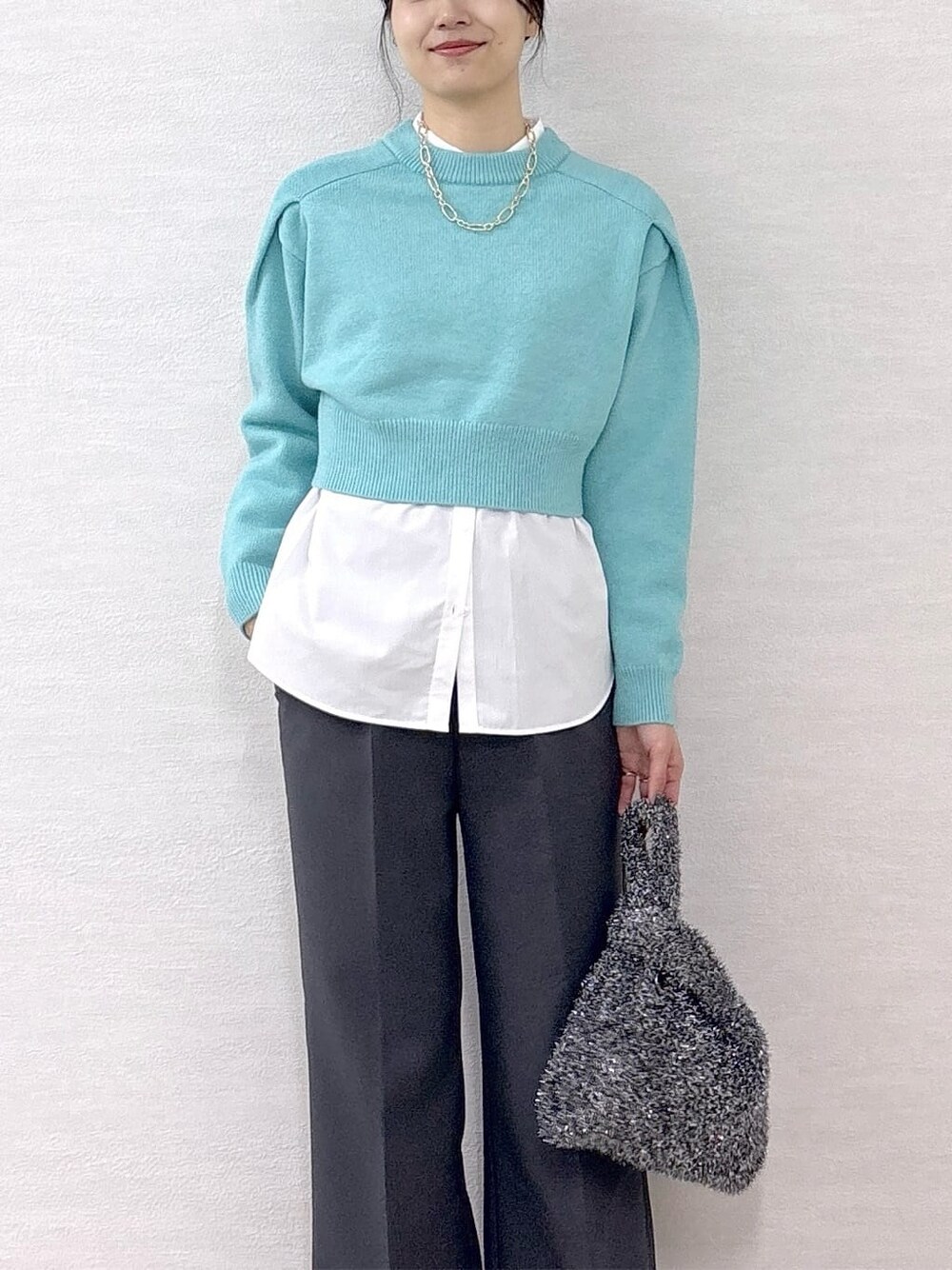 ブラック系のチェスターコート、ブルー系のニット/セーター、ホワイト系のシャツ/ブラウスを着用したレディースの冬コーディネートの7枚目の写真
