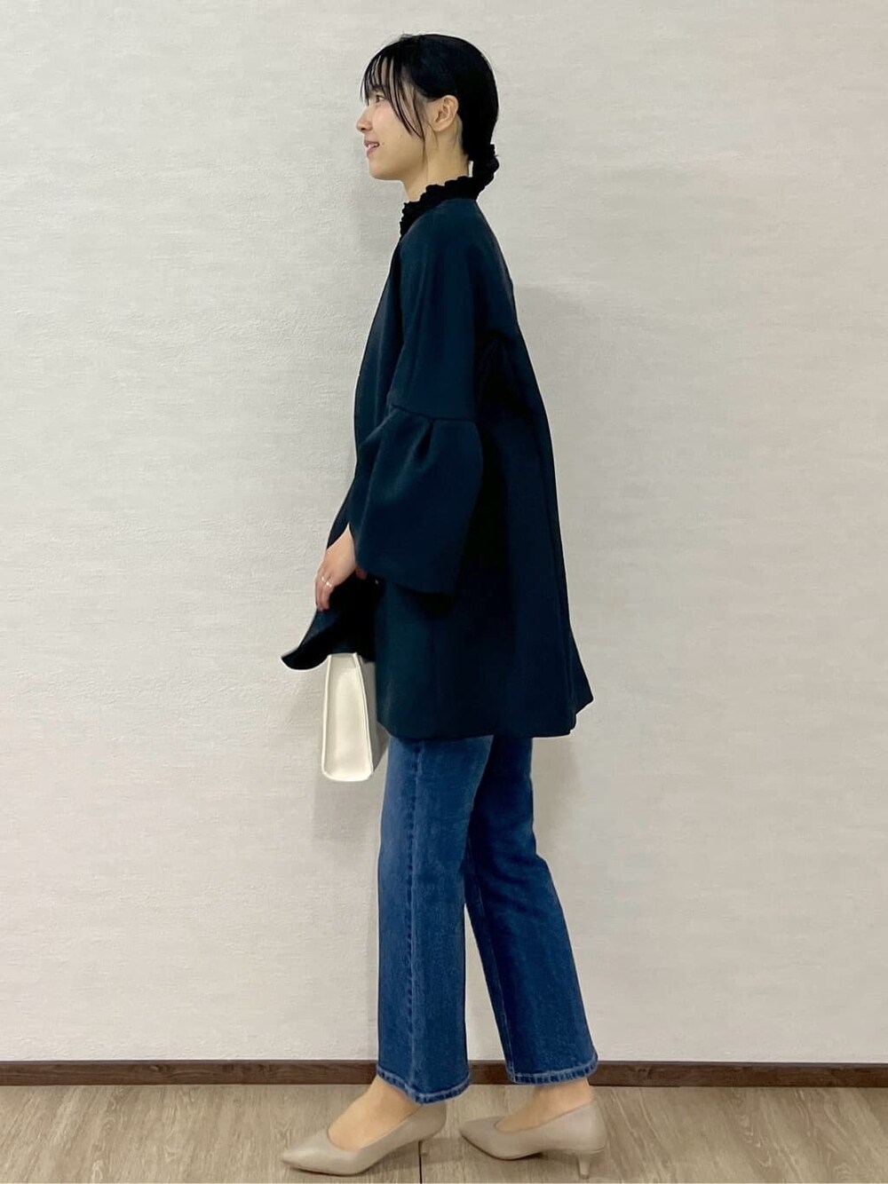 ブルー系のノーカラーコート、ブラック系のTシャツ/カットソー、ブルー系のデニムパンツを着用したレディースの冬コーディネートの3枚目の写真