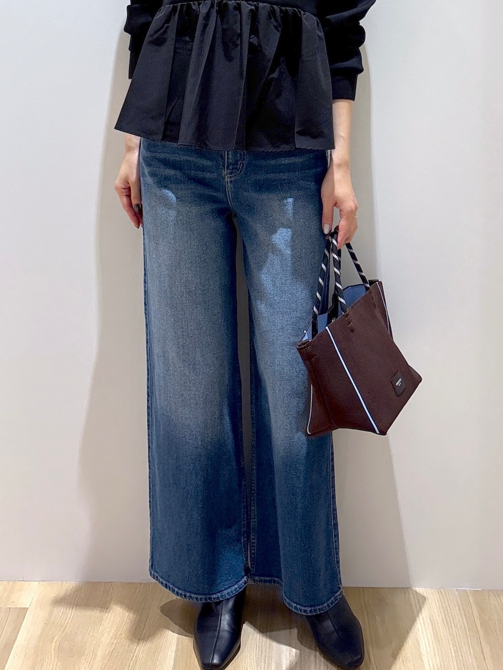 ブラック系のTシャツ/カットソー、ブルー系のデニムパンツ、ブラウン系のトートバッグを着用したレディースの秋コーディネートの7枚目の写真