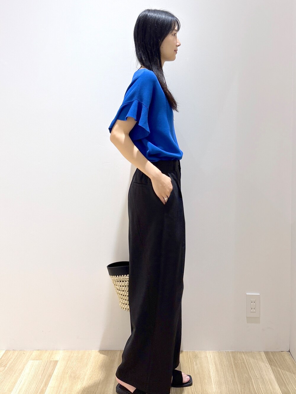 ブルー系のニット/セーター、ブラック系のその他パンツ、ブラック系のトートバッグを着用したレディースの夏コーディネートの5枚目の写真
