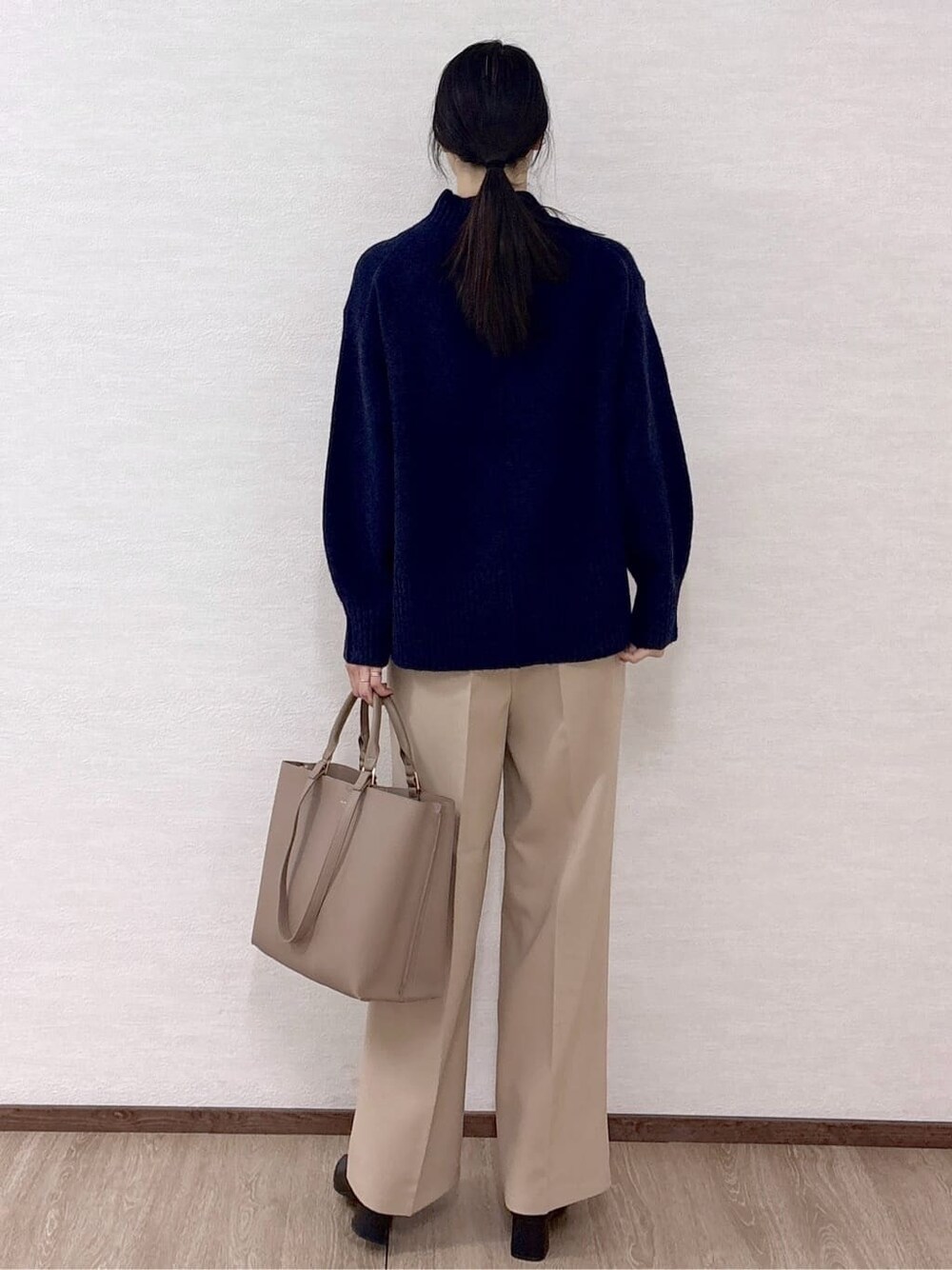 ブルー系のニット/セーター、ベージュ系のその他パンツ、ベージュ系のトートバッグを着用したレディースの冬コーディネートの4枚目の写真