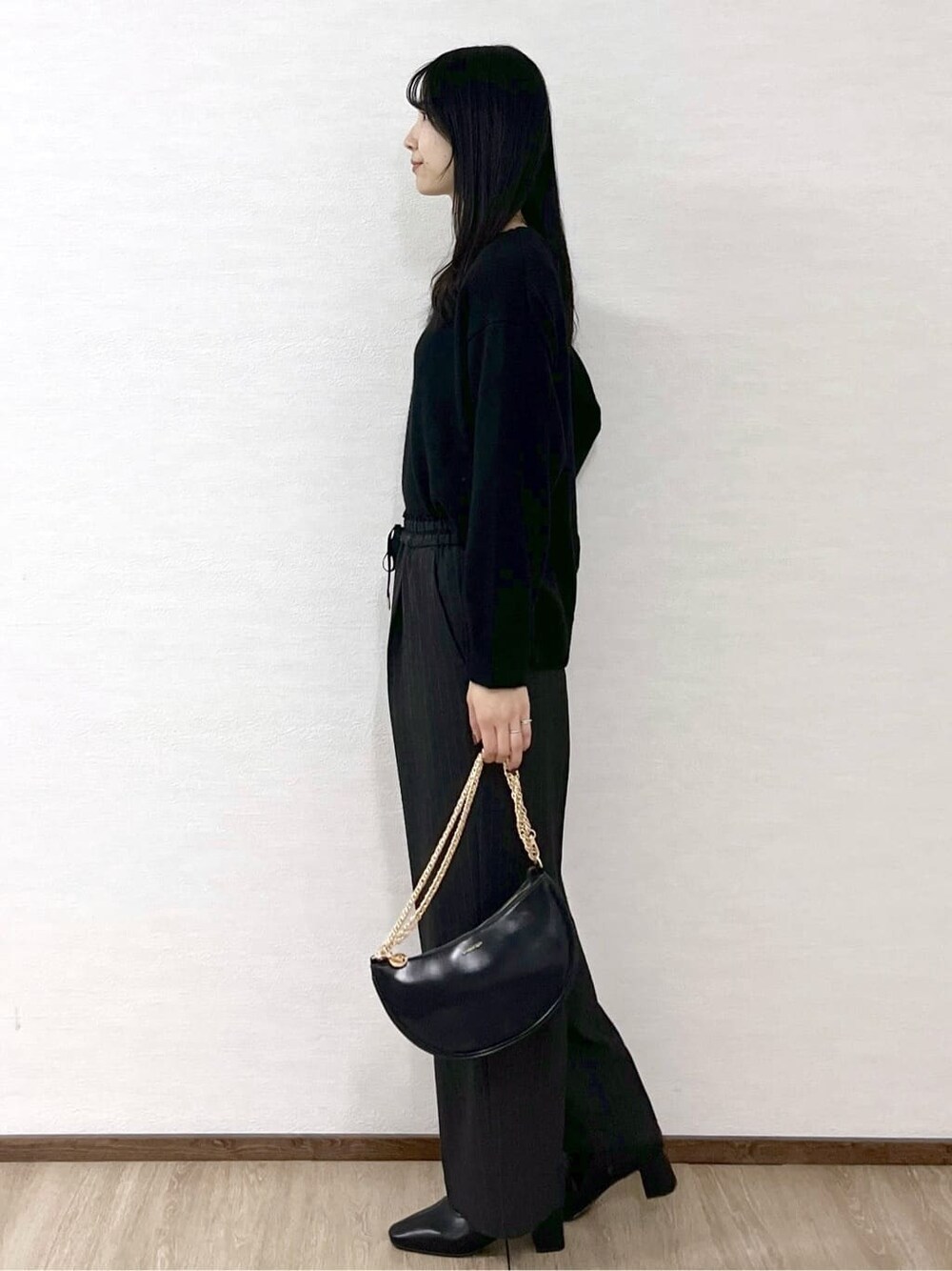 ブラック系のニット/セーター、グレー系のその他パンツ、ブラック系のハンドバッグを着用したレディースの冬コーディネートの3枚目の写真