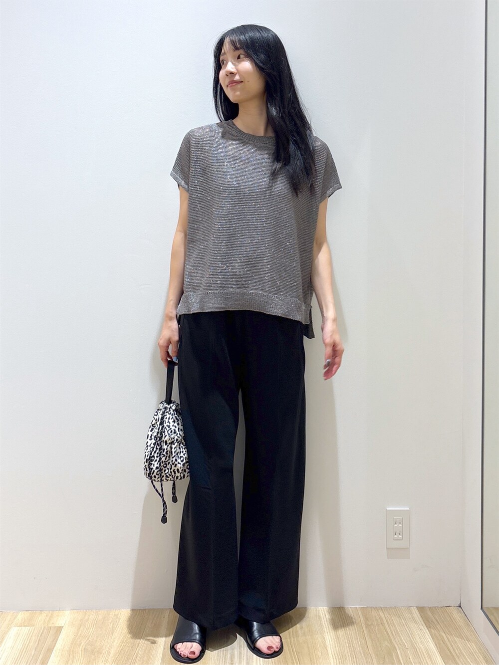 グレー系のニット/セーター、ブラック系のその他パンツ、ベージュ系のショルダーバッグを着用したレディースの夏コーディネートの2枚目の写真