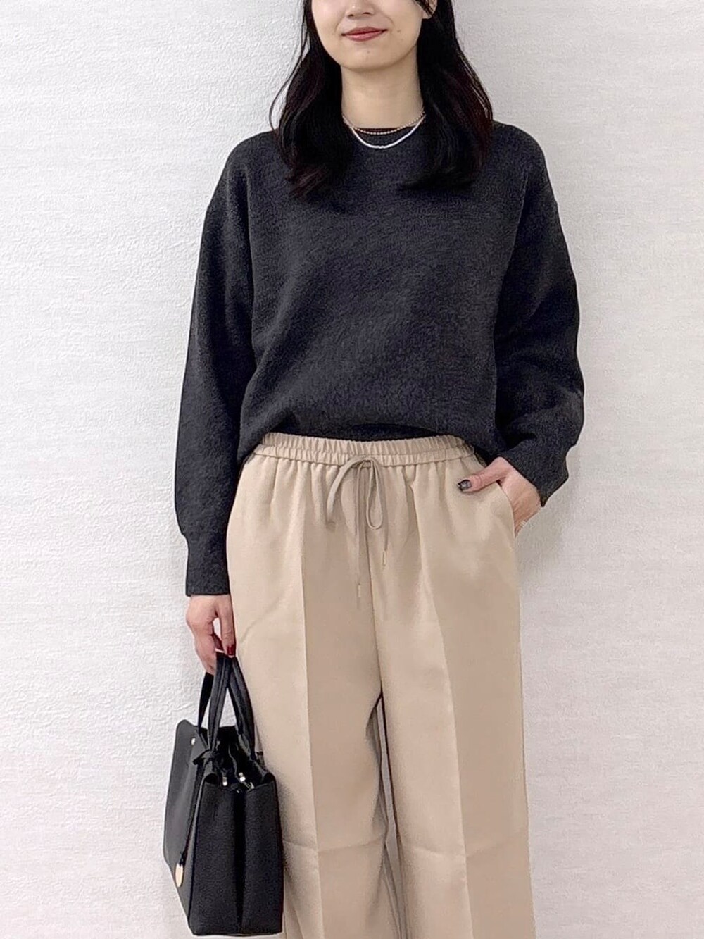 グレー系のニット/セーター、ベージュ系のその他パンツ、ブラック系のトートバッグを着用したレディースの冬コーディネートの6枚目の写真